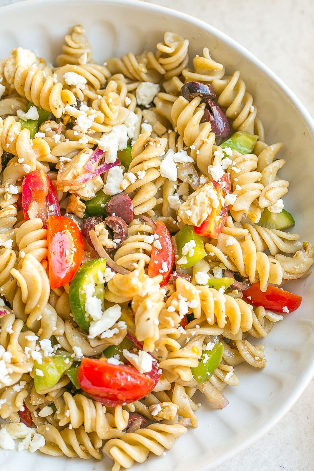 Greek salad with pasta in a bowl.