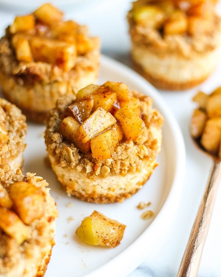 Close-up of mini apple cheesecake bites on a circular white plater.