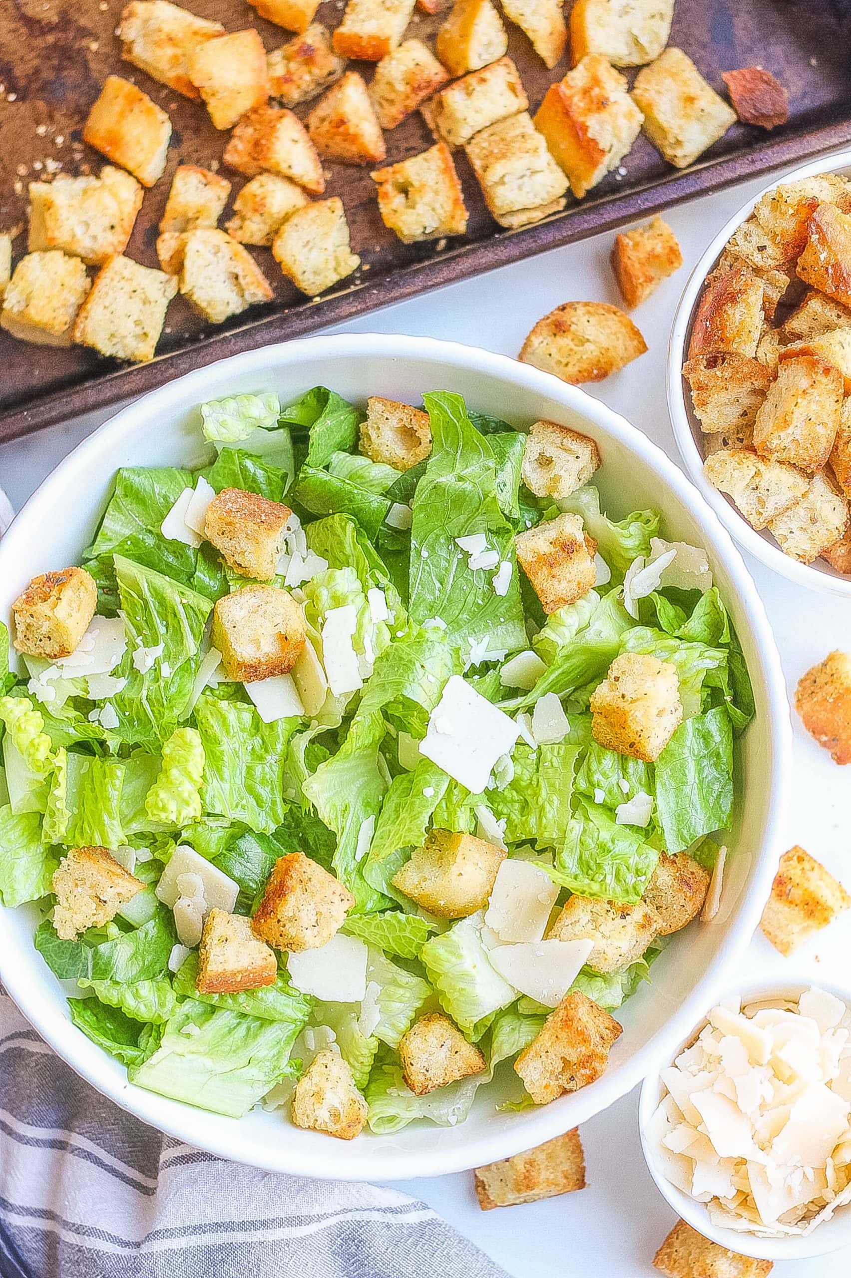 top view of homemade croutons recipe on bed of greens with parmesan