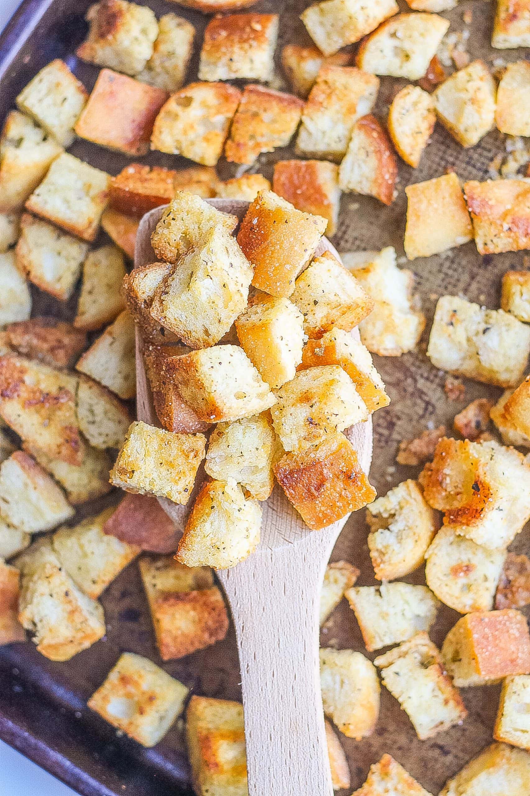 croutons on baking sheet with wooden spoon