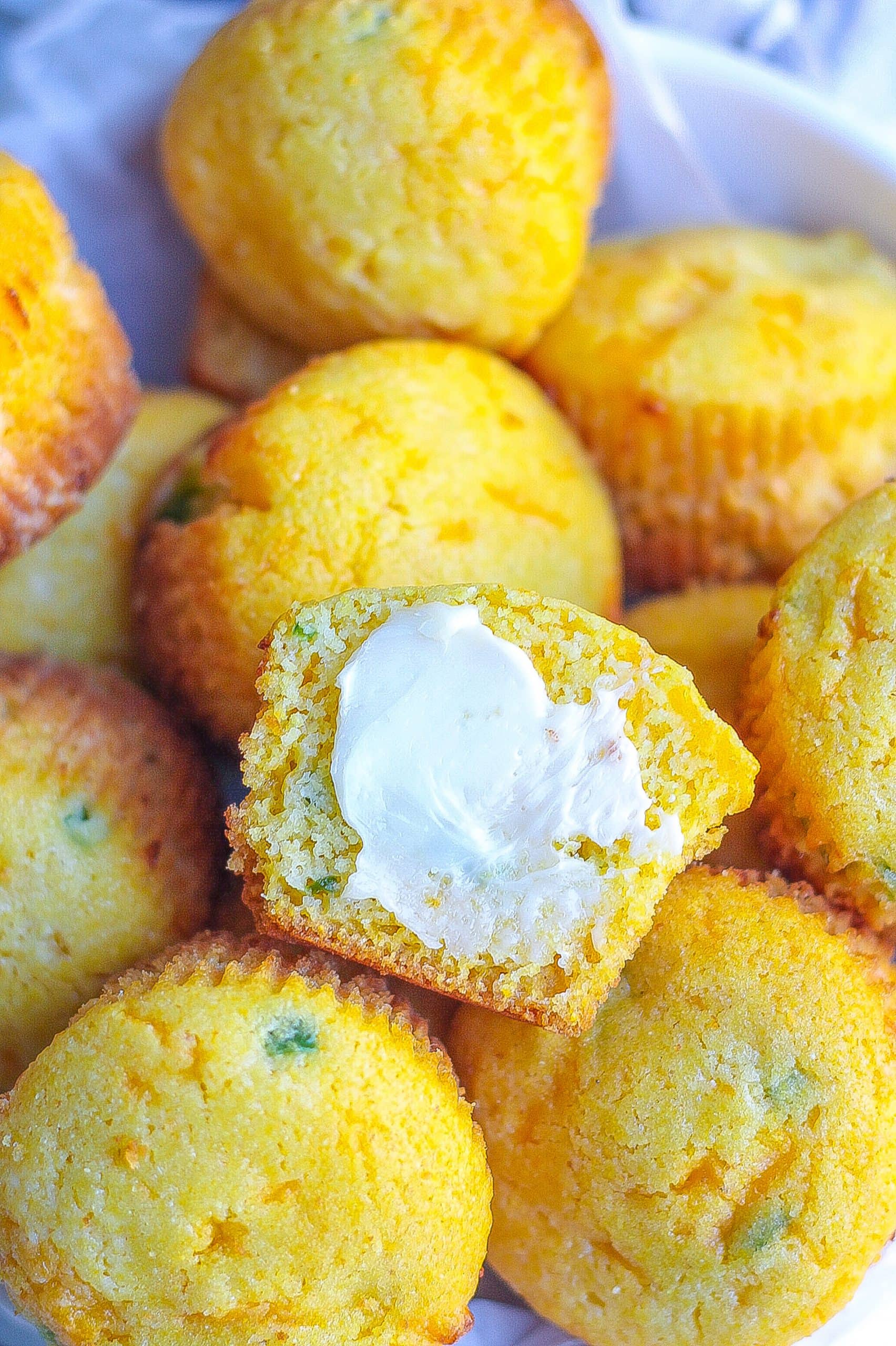 one bowl full of jalapeño cheddar cornbread muffins with butter on muffins