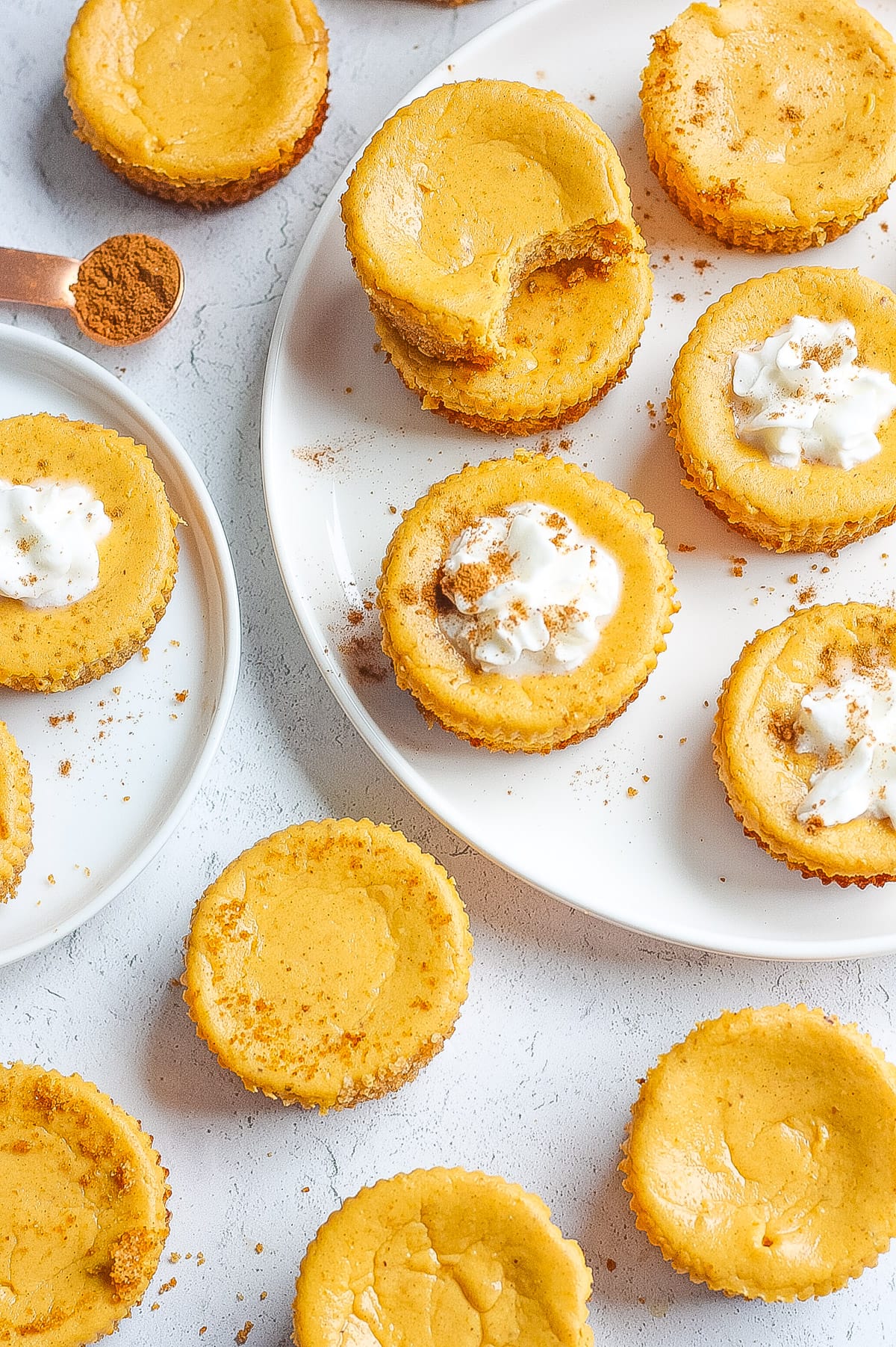 top view of mini cheesecake bites with pumpkin and spices on white surface and plate