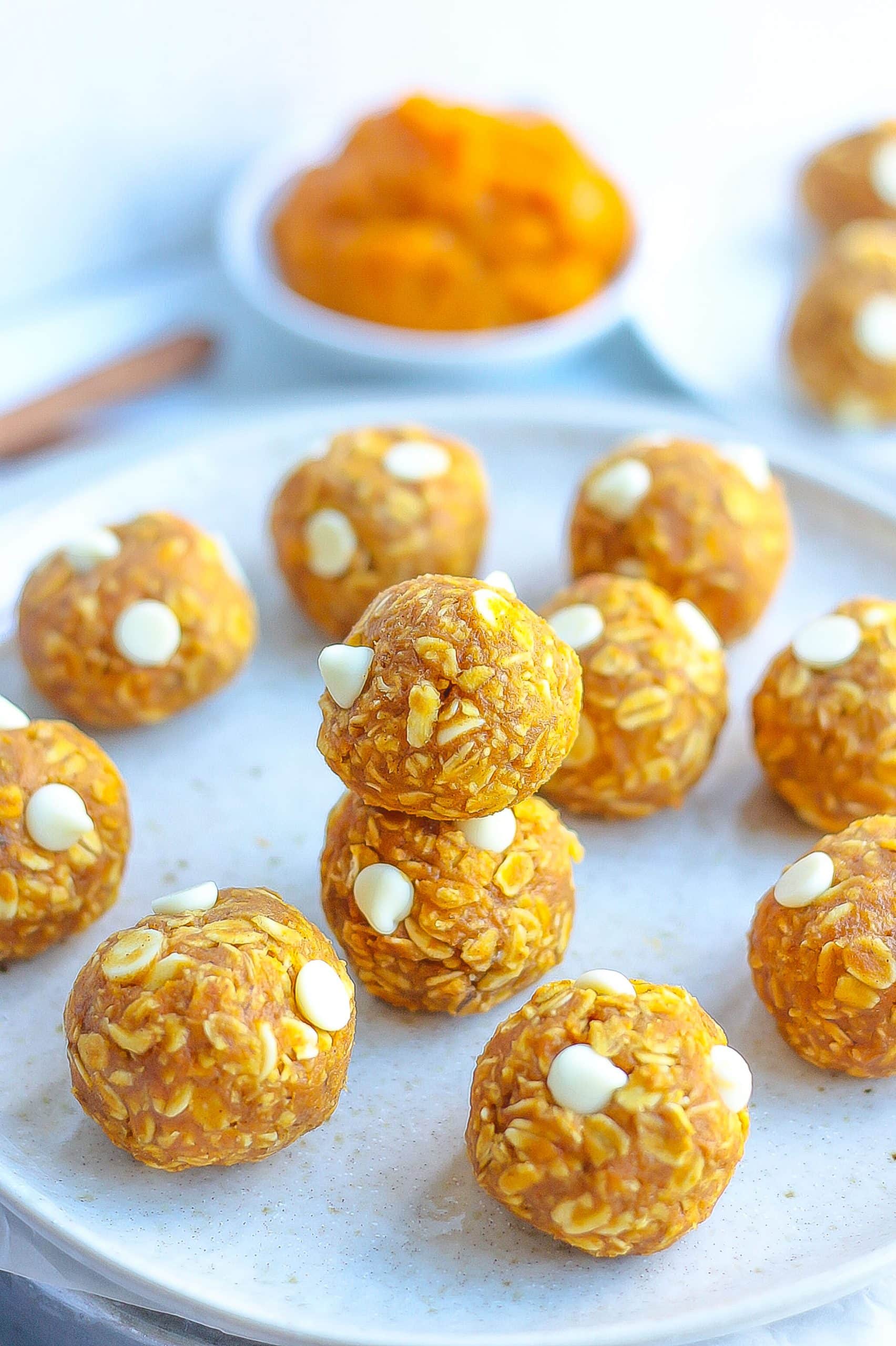 pumpkin energy bites on white plate with pumpkin puree in background