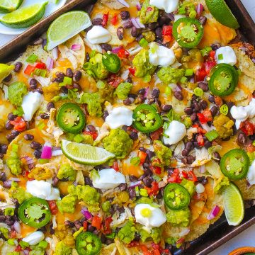 sheet pan filled with baked chicken, cheese, sour cream, jalapeńo, avocado, onion, black beans