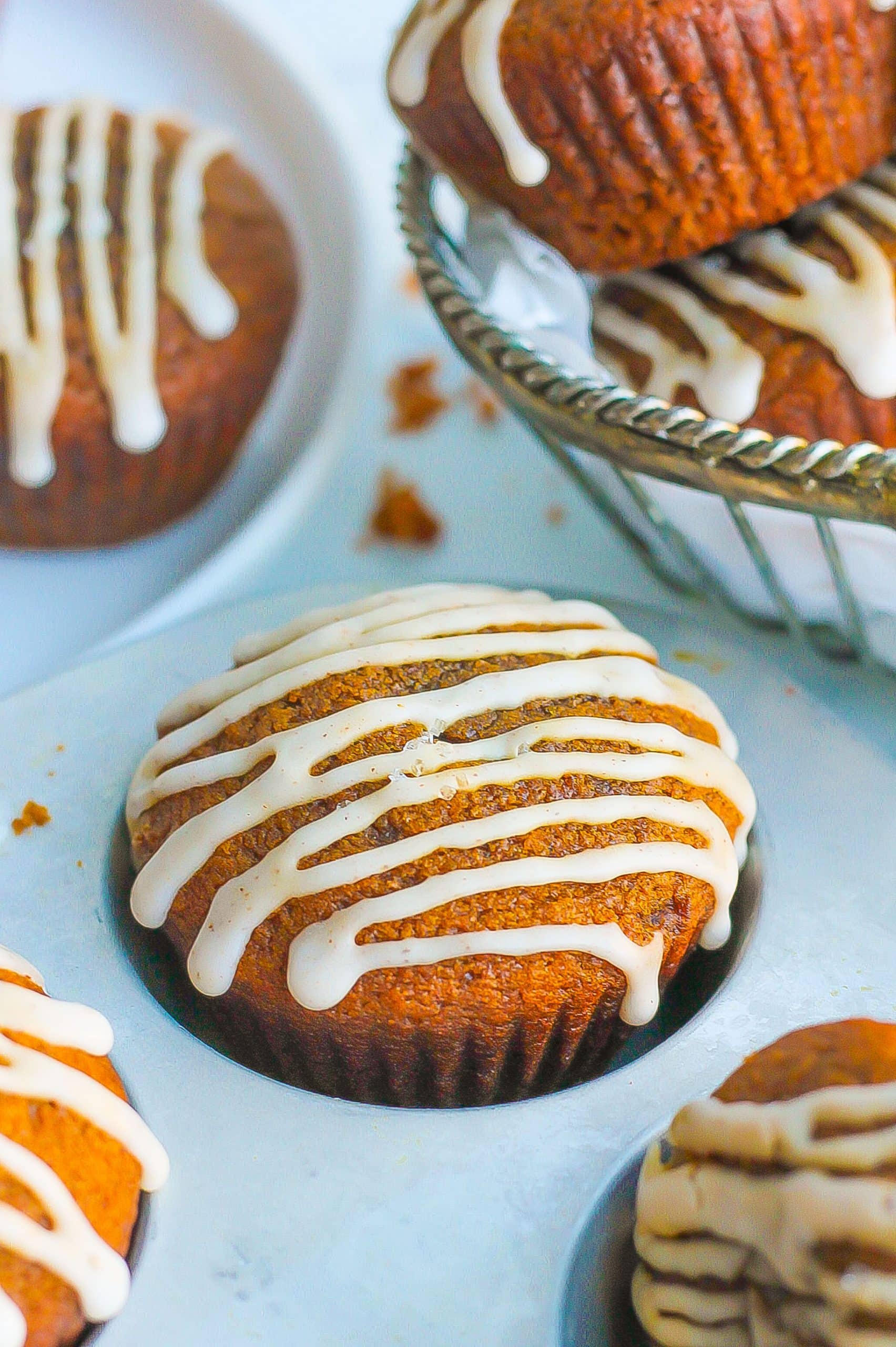 gingerbread muffins in muffin pan with vanilla icing drizzle