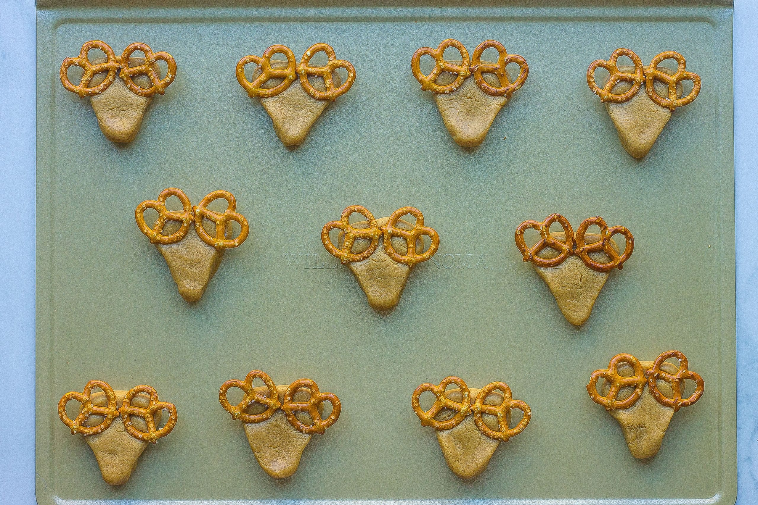 shaped peanut butter dough with pretzels placed on top.
