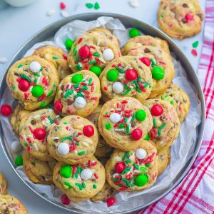 one tray filled with baked Santa cookies with M&Ms, sprinkles, and chocolate chips