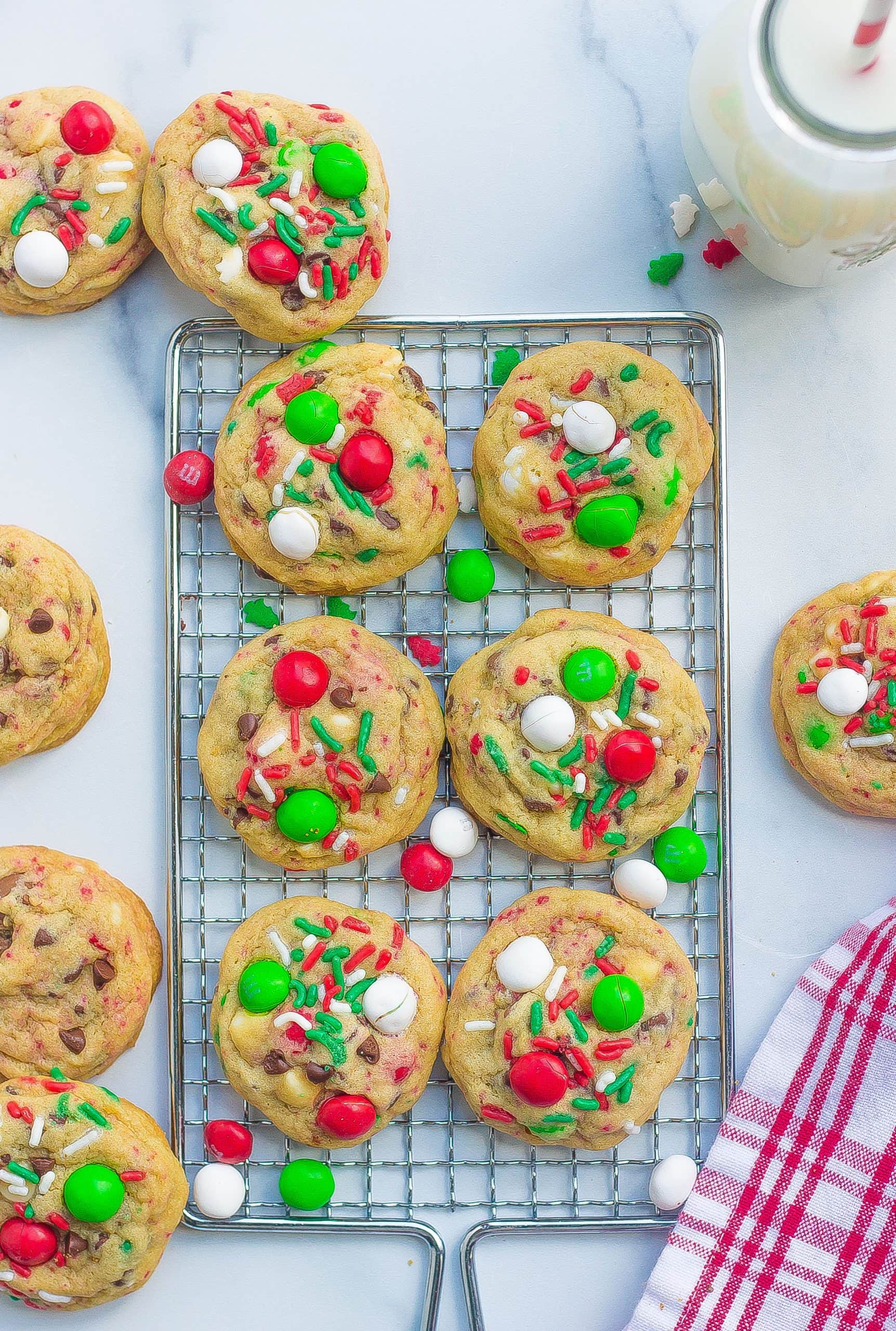 six baked cookies on wire rack with M&Ms, sprinkles, chocolate chips 