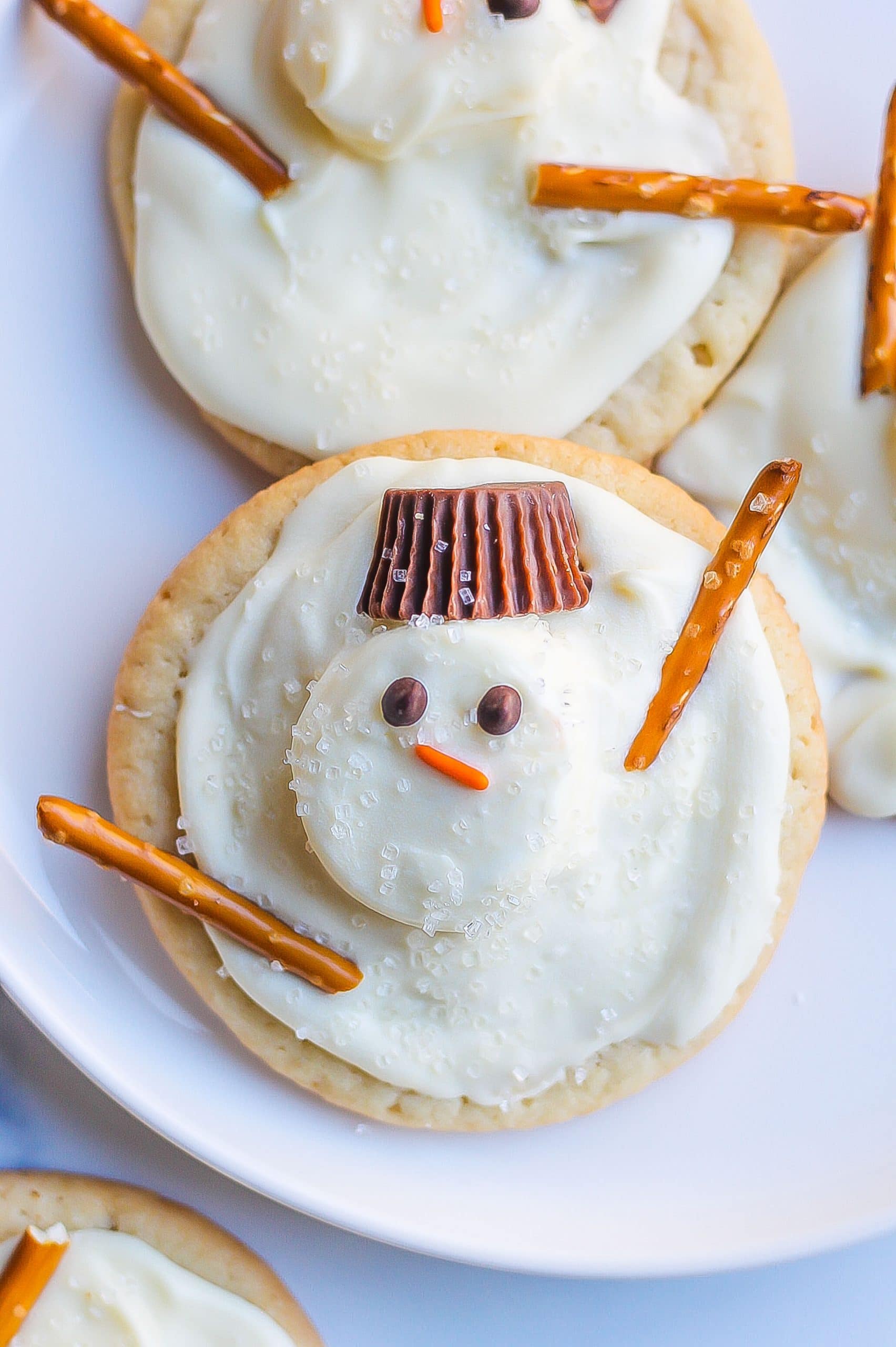 snowman cookies on white plate with Reese's hats and pretzel sticks