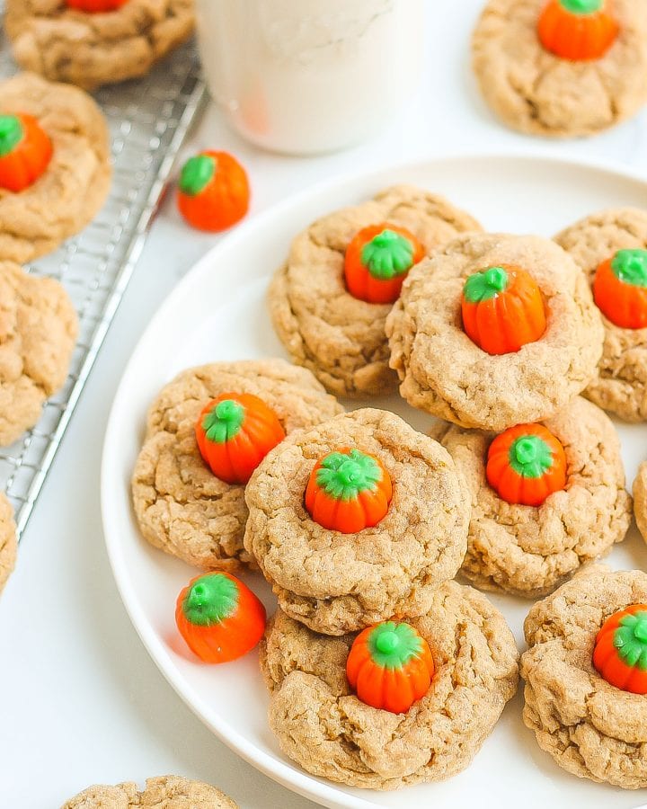 Spice cookies with pumpkin candies on circular white plate.