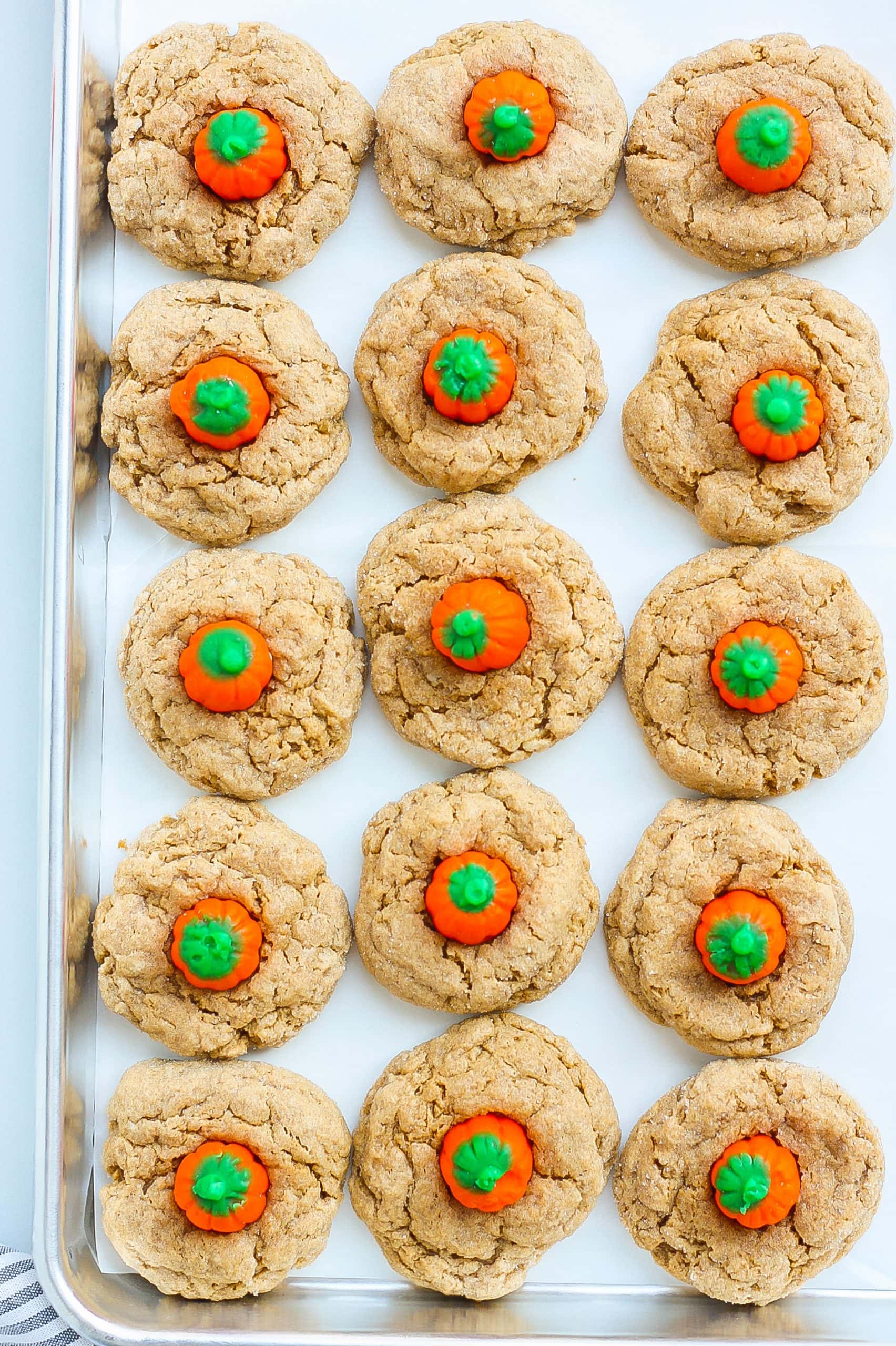 Spice cookies with pumpkin candy on baking sheet. 
