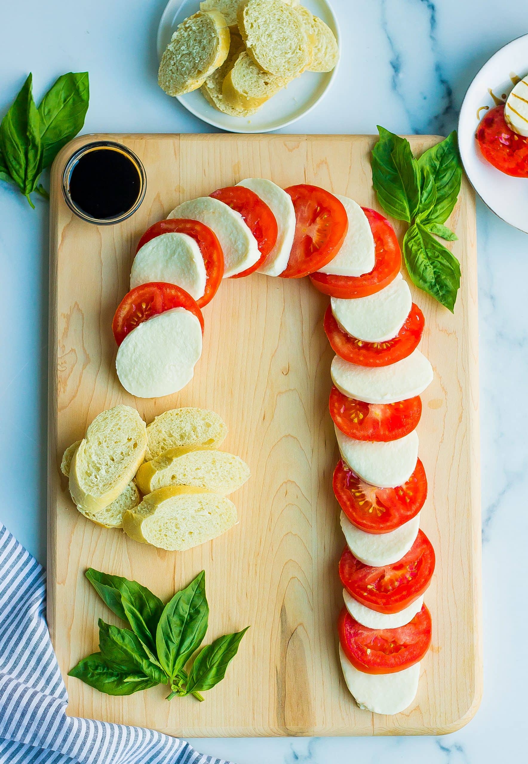 candy cane caprese salad on wooden cutting board with basil and bread