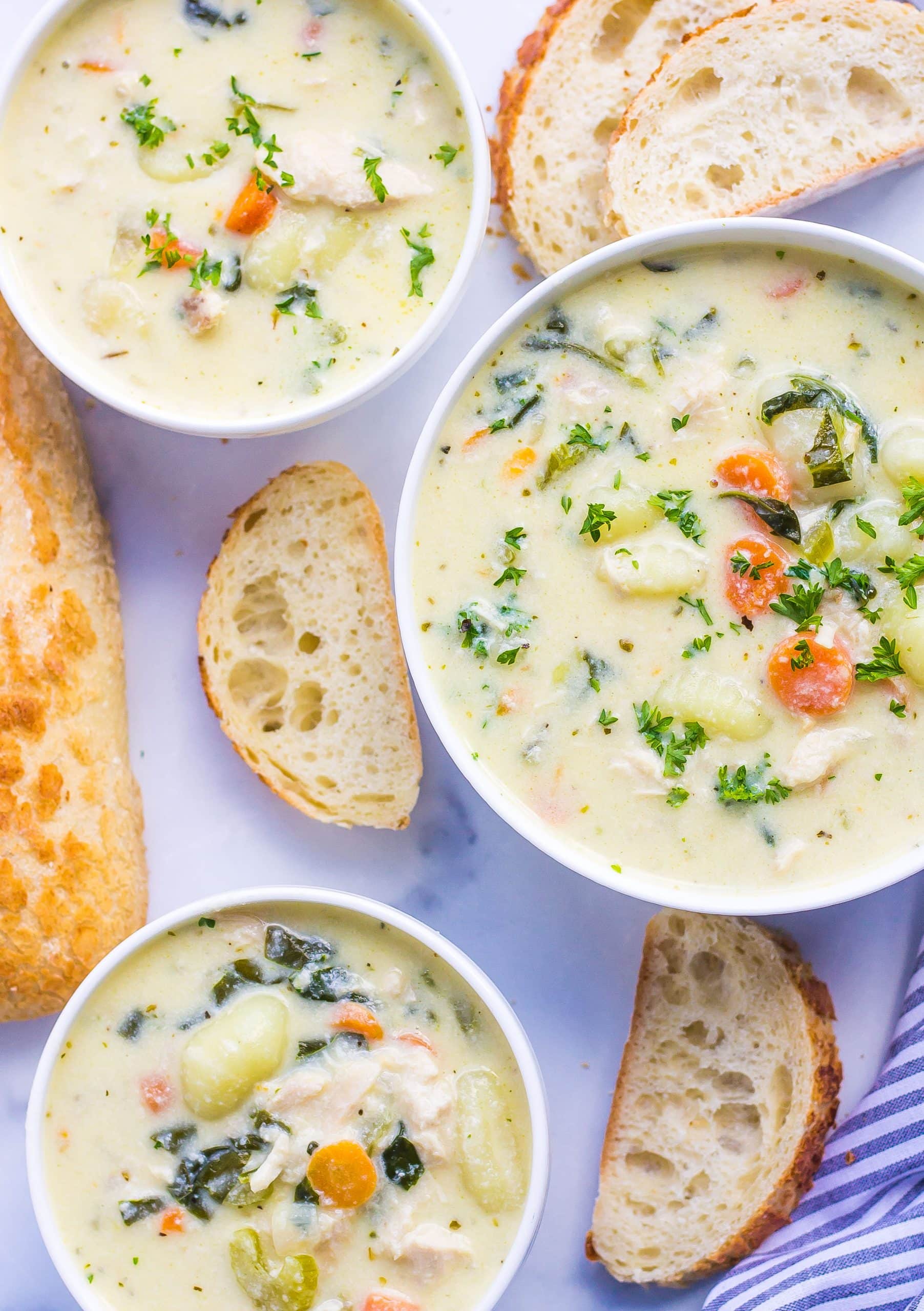 three bowls of chicken gnocchi soup served with crusty bread 