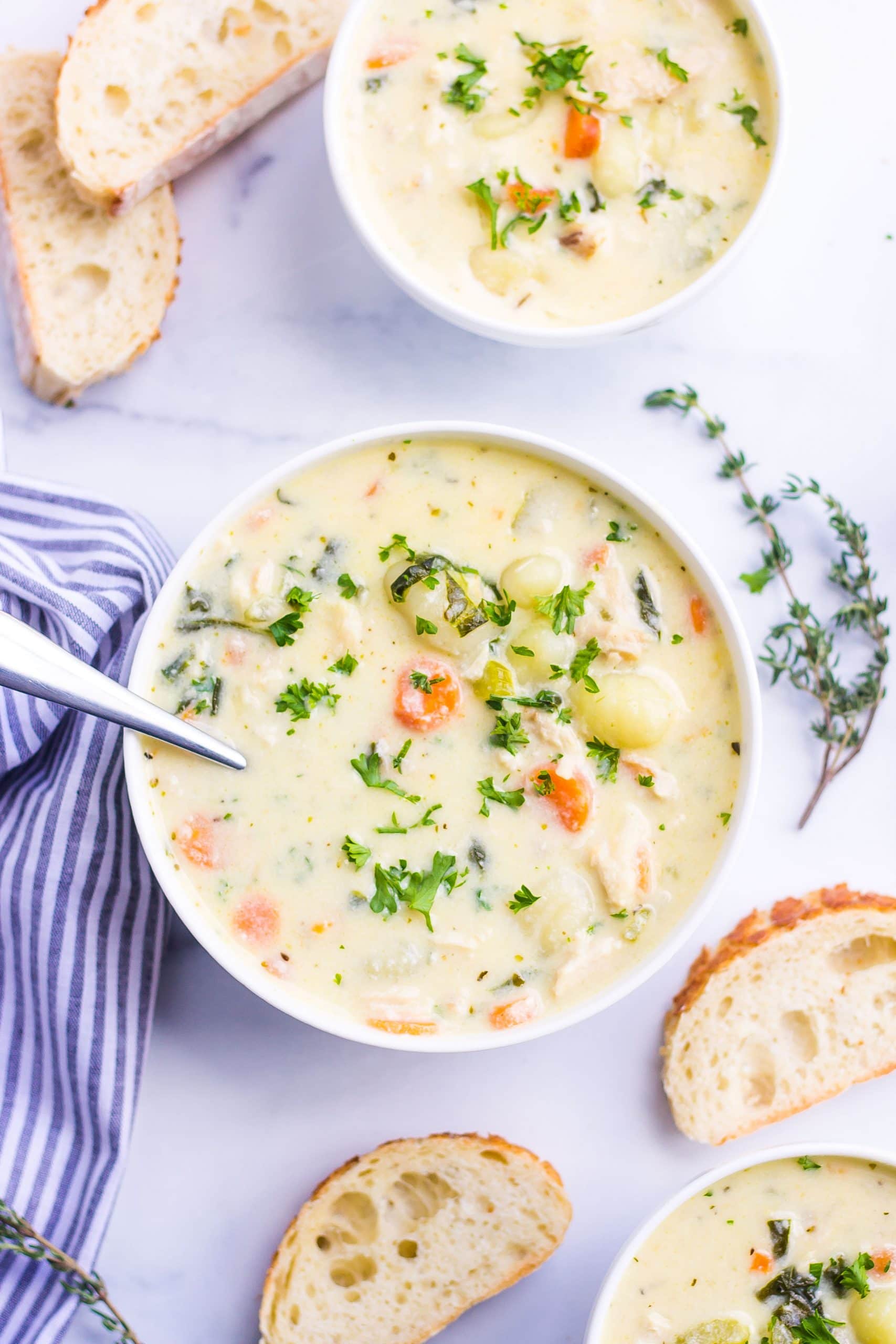 two bowls of gnocchi soup with chicken and carrots with thyme 