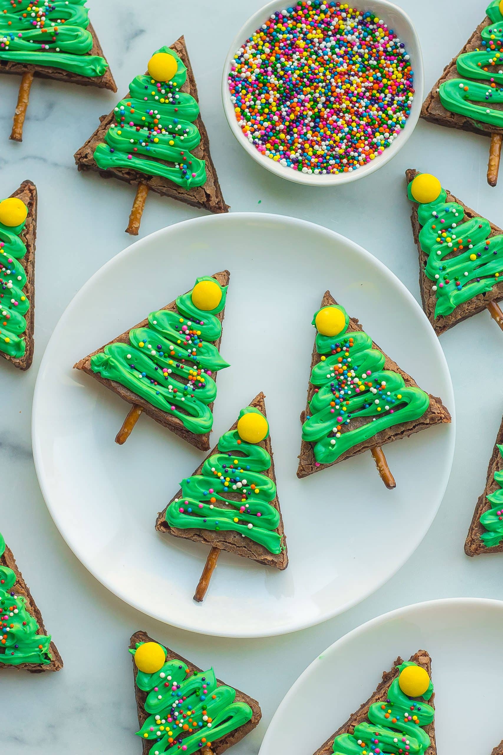 Overhead close-up of 3 christmas tree brownies on a circular white plate.