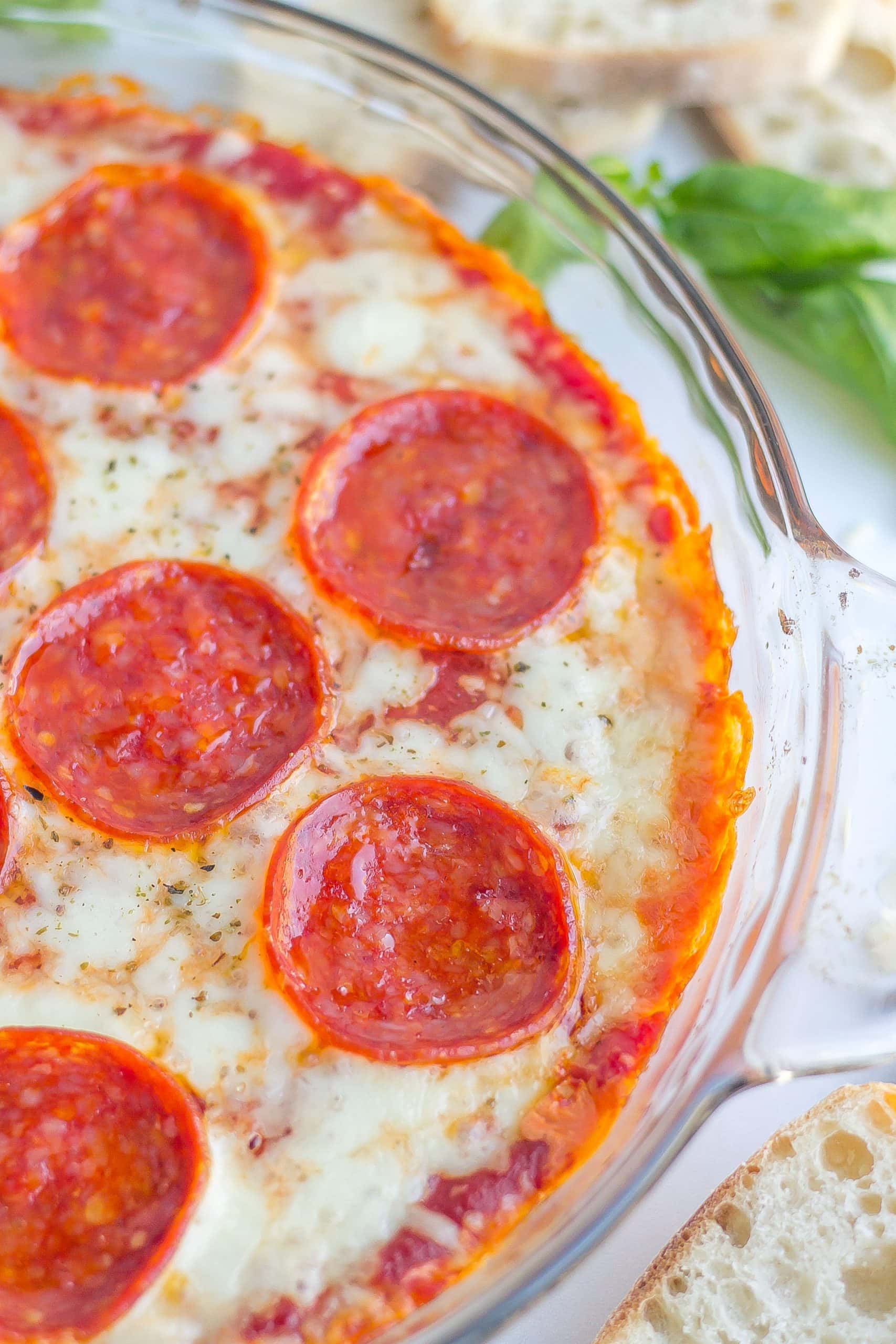 baked pizza dip in glass dish with pepperoni slices 