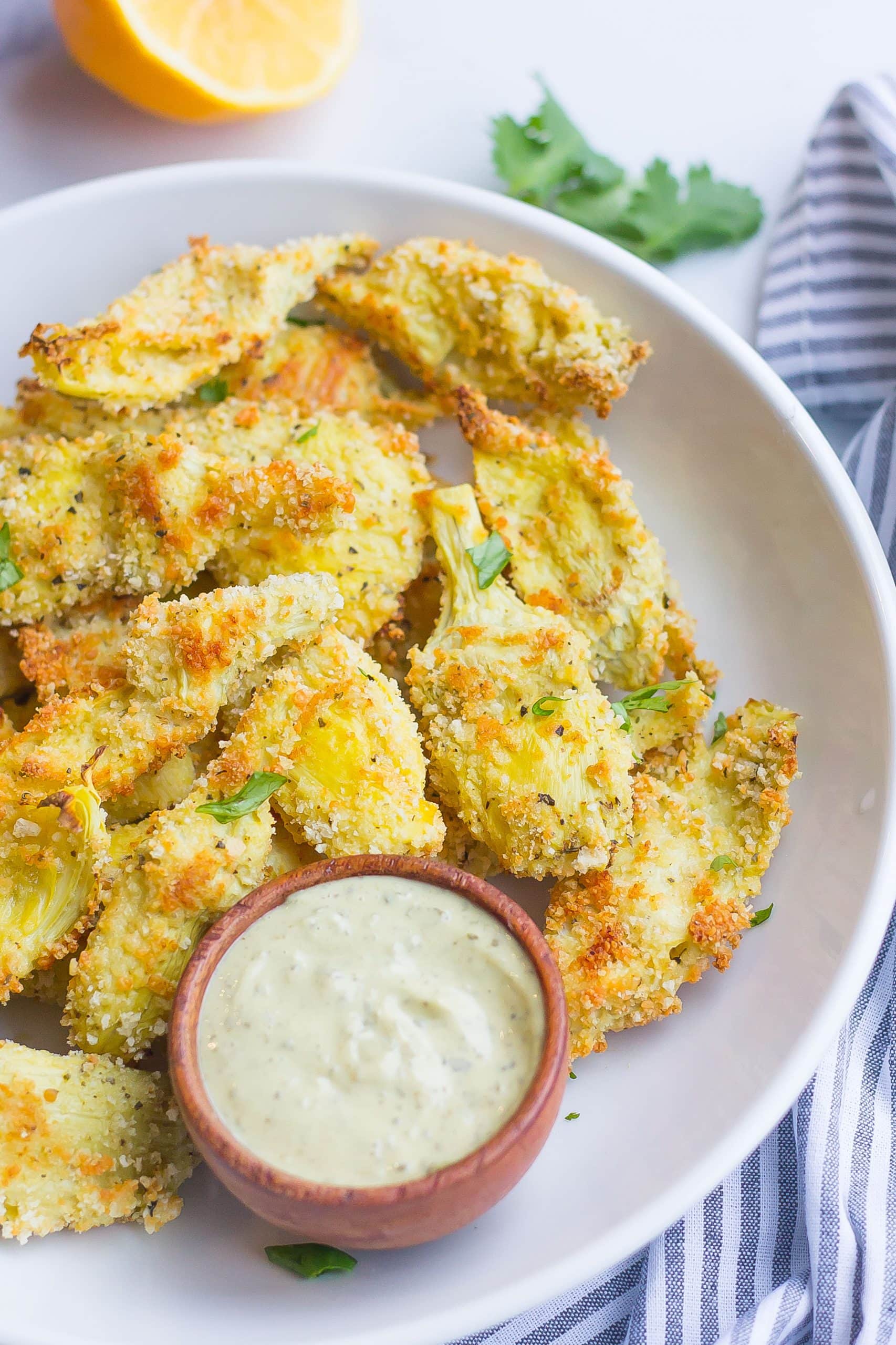 baked parmesan artichoke hearts on a plate with aioli sauce