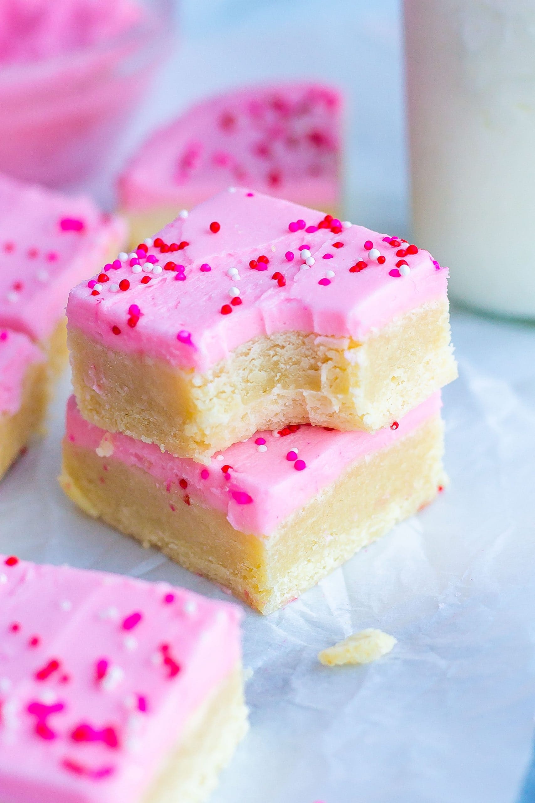 stack of cookie bars with pink frosting and sprinkles