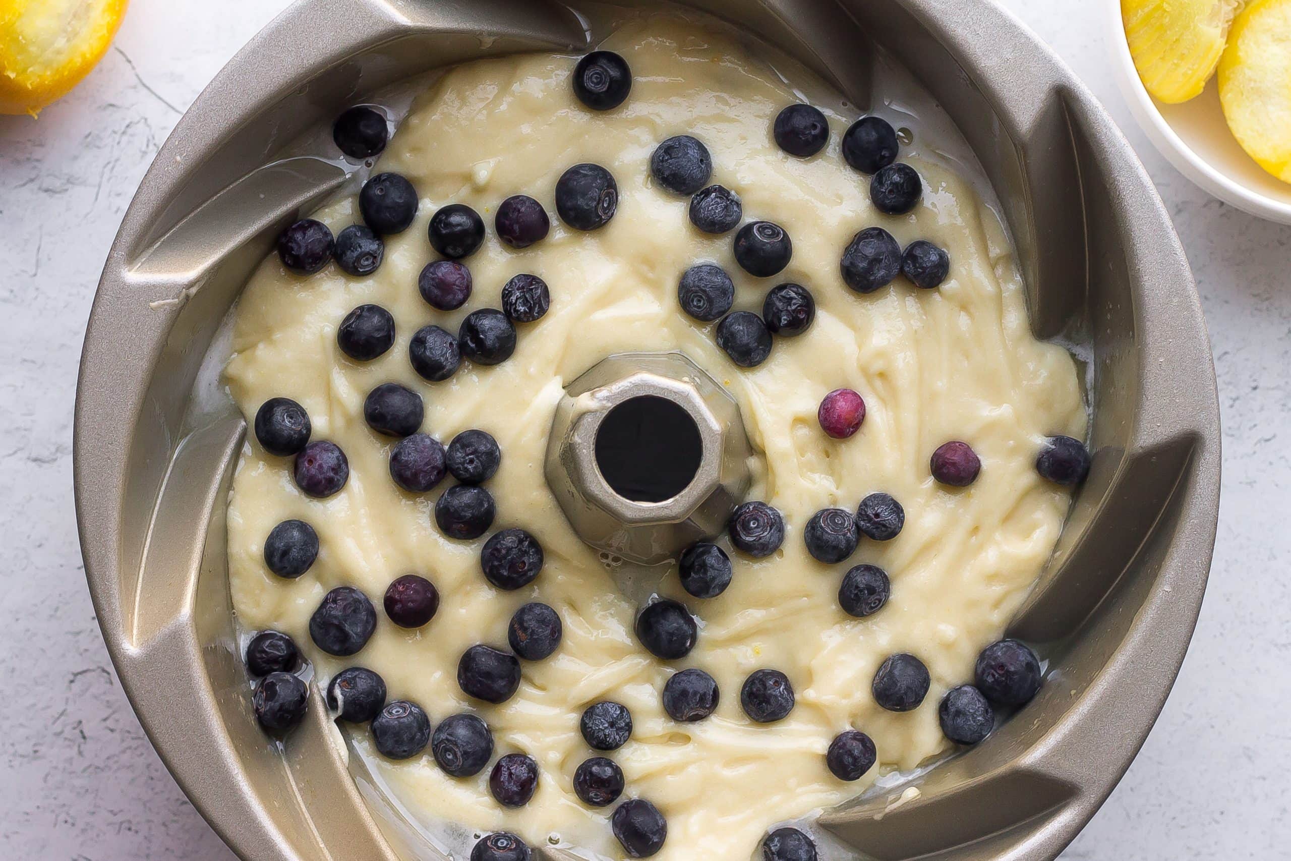 lemon cake batter in a bundt pan with blueberries on top