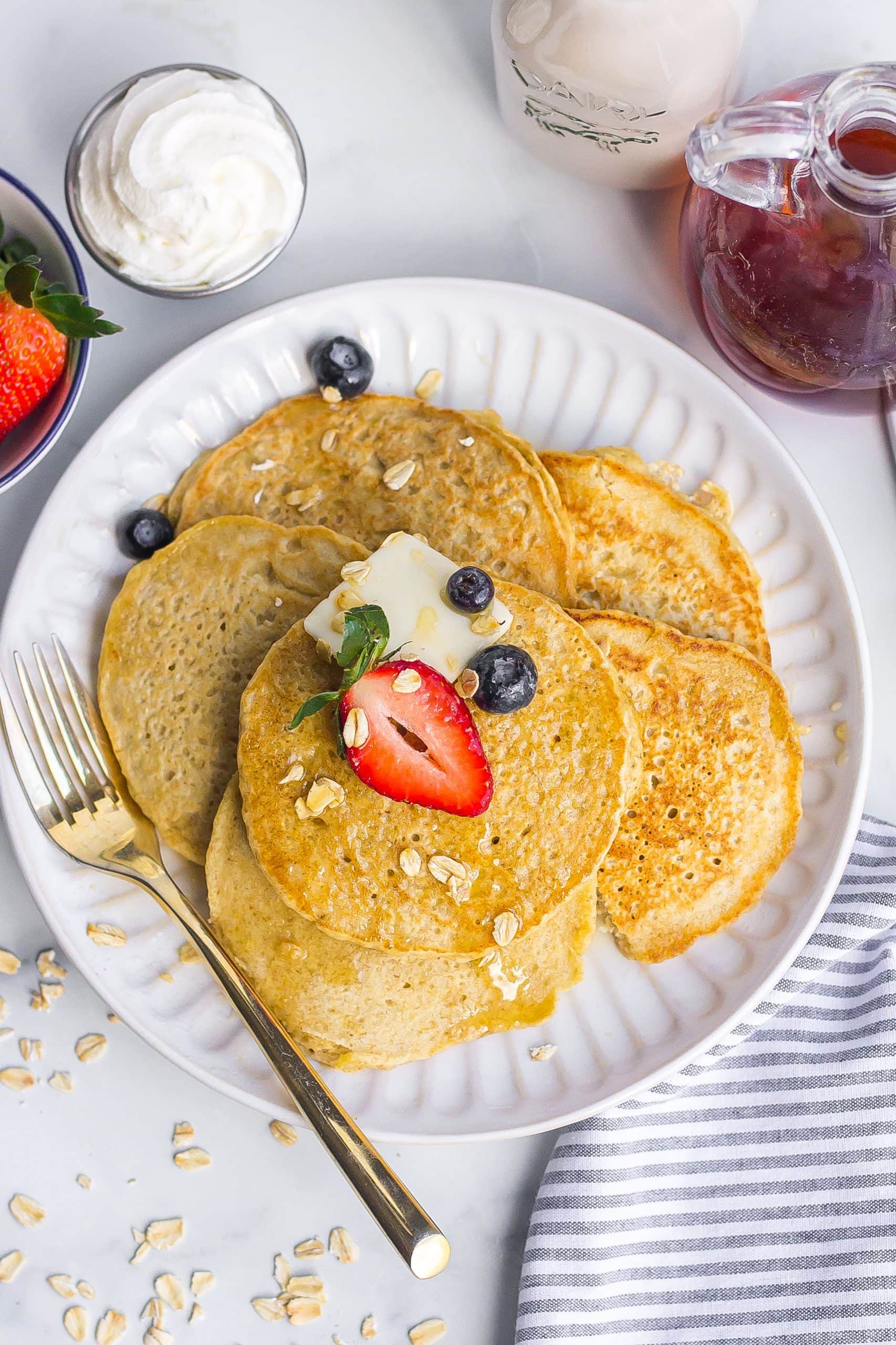oatmeal pancake recipe with whipped cream, berries, syrup and milk