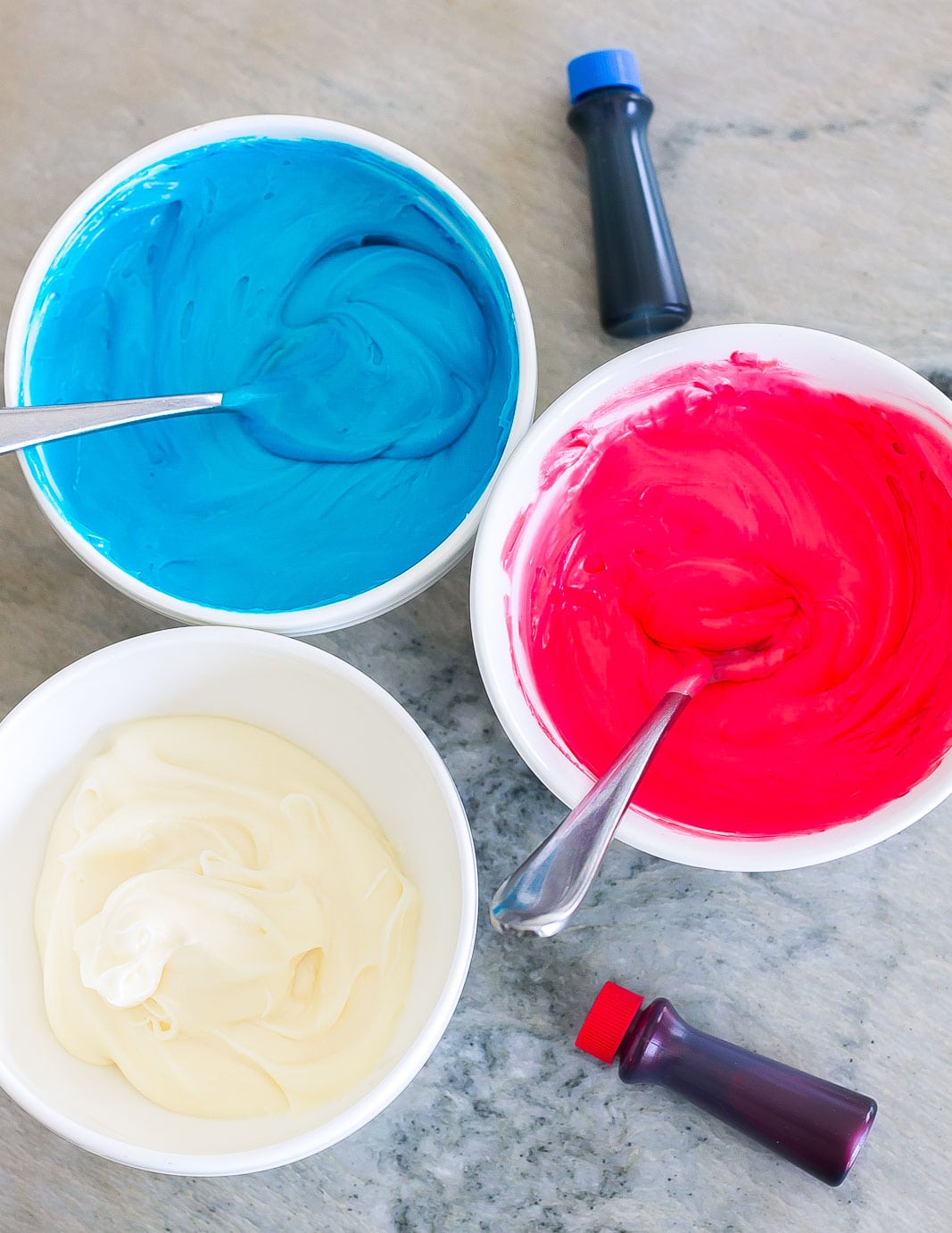 red, white, and blue frosting in bowls