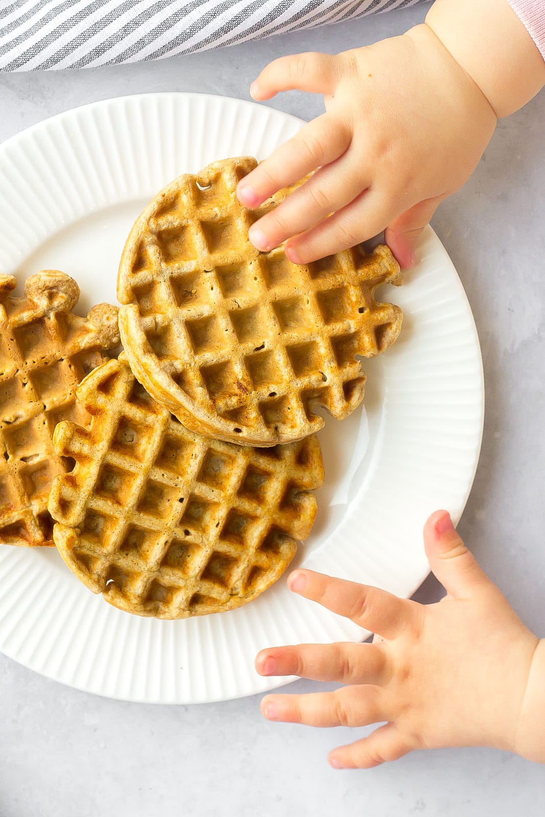 toddler friendly waffles on white plate with toddler hands