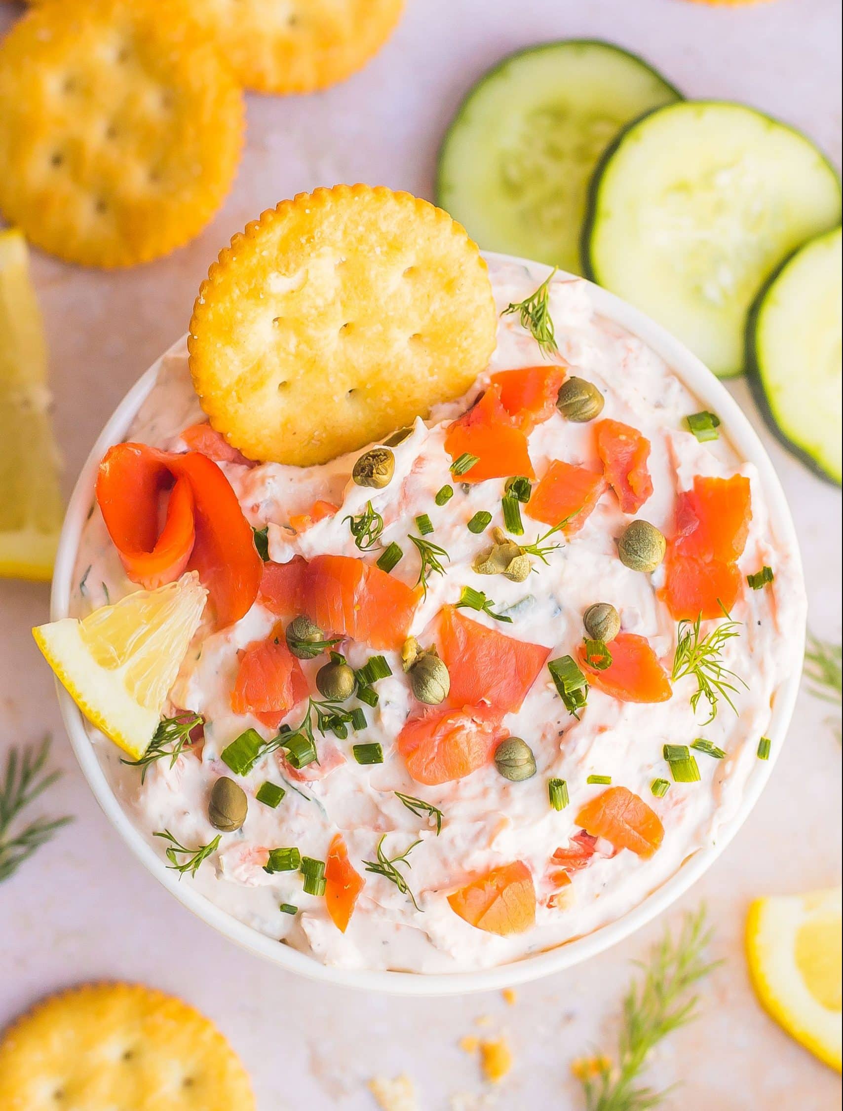 Smoked Salmon Dip in a bowl with crackers and cucumber slices