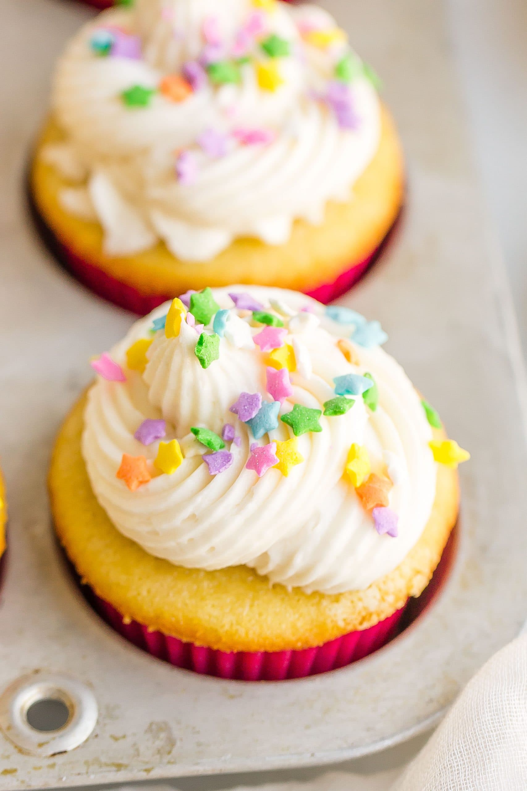 close up of frosted vanilla cupcake with sprinkles 