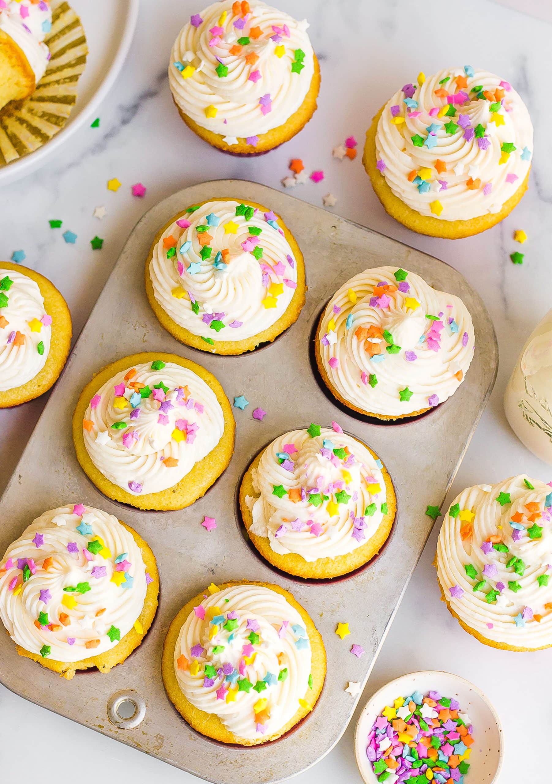 baked vanilla cupcakes in cupcake pan with sprinkles 