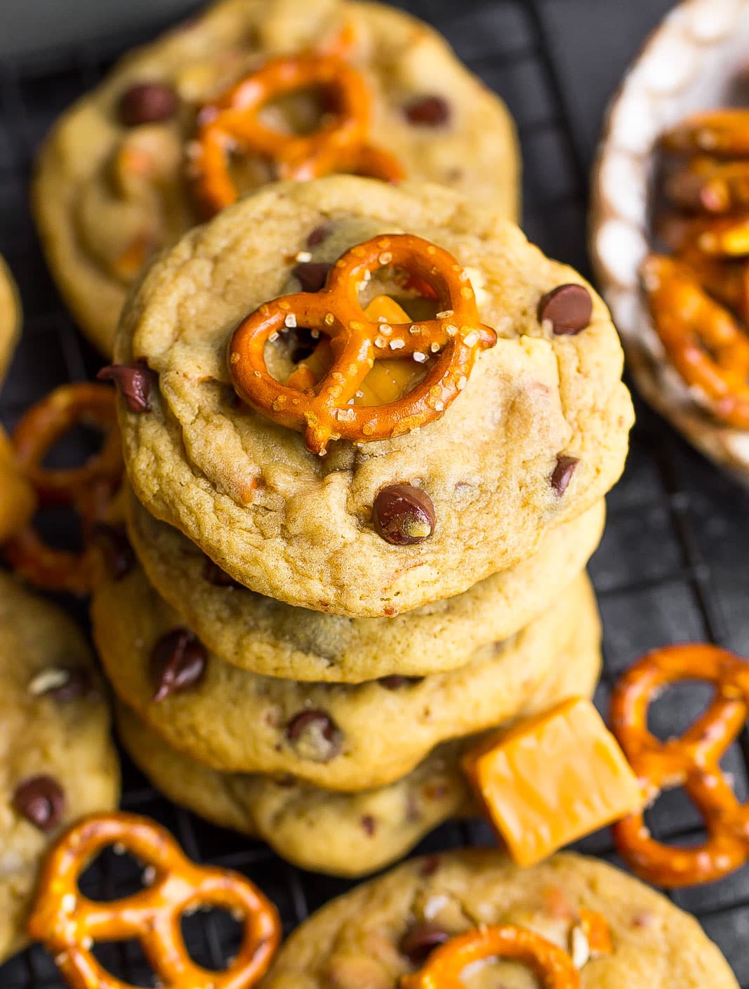 Stack of Chocolate Chip Pretzel Cookies with pretzel twist on top on a cooling rack,