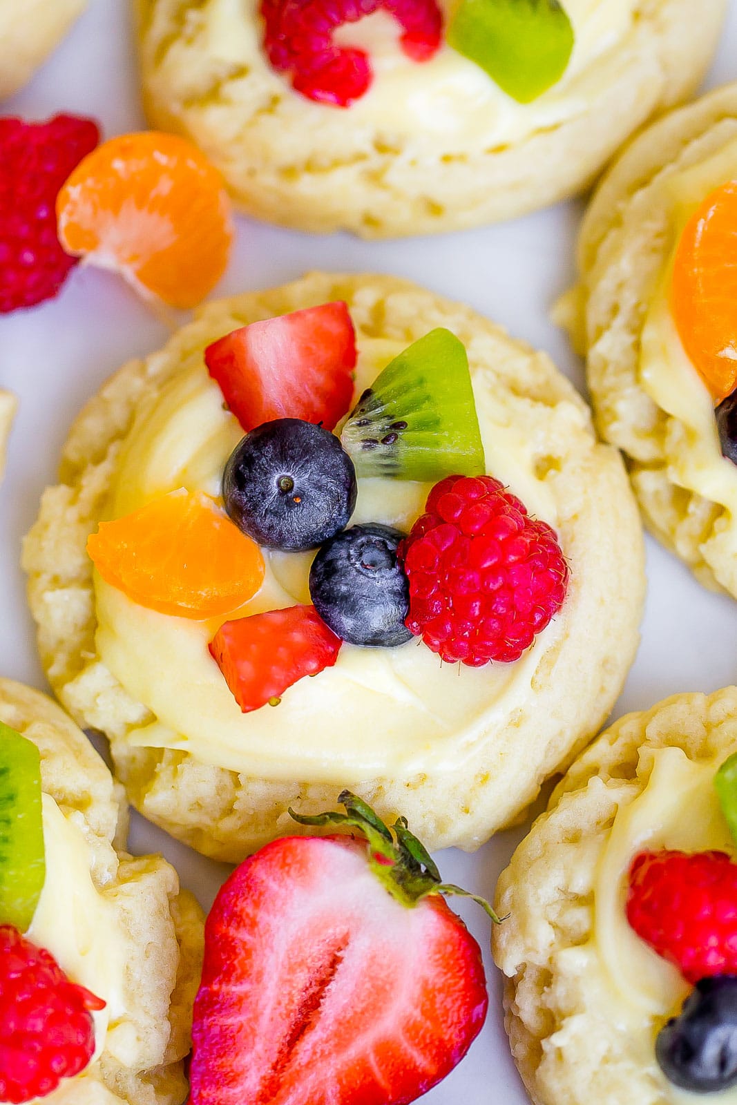 close up view of frosted sugar cookies with fresh fruit on top