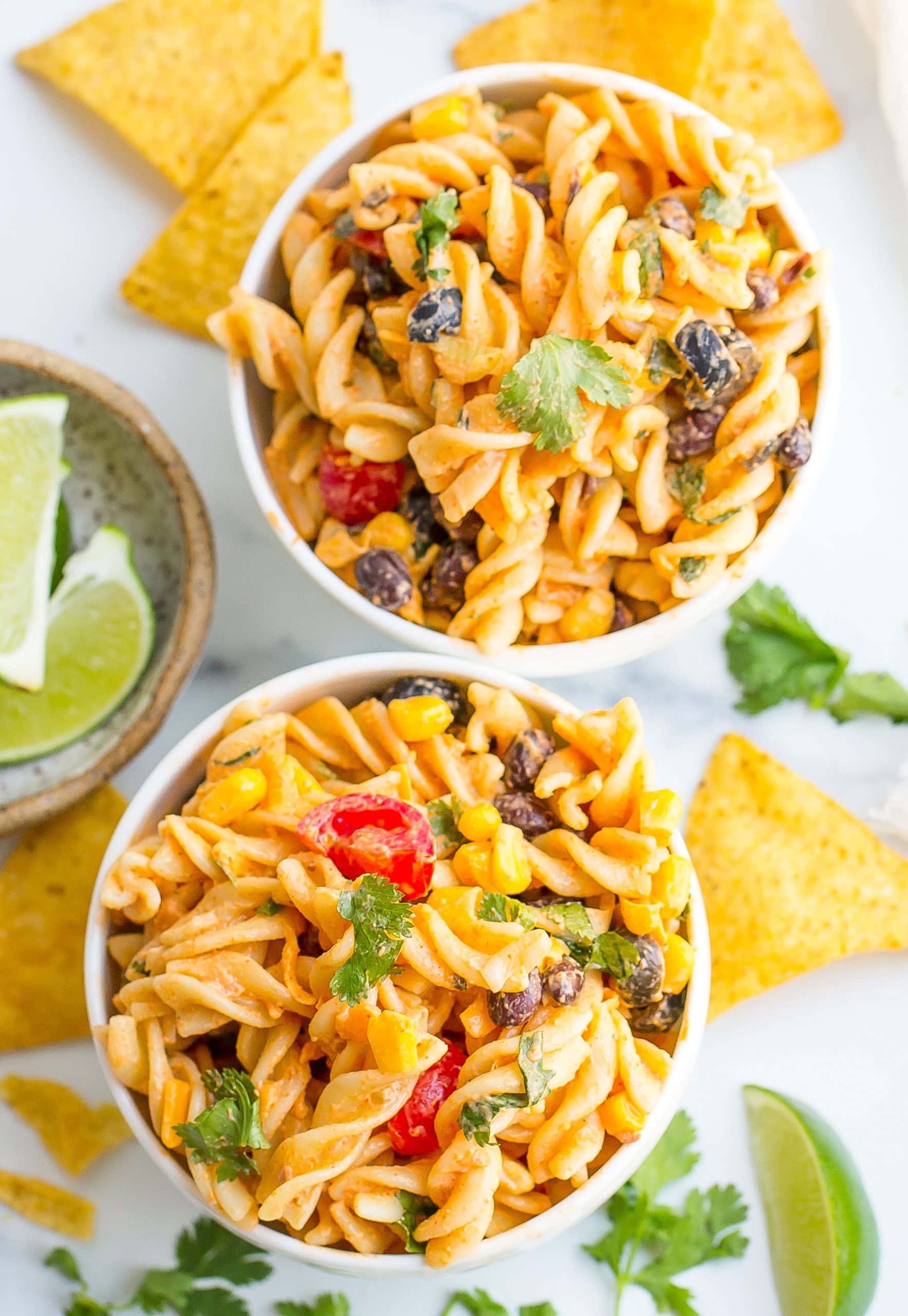 taco pasta salad in small white bowls with chips on the side