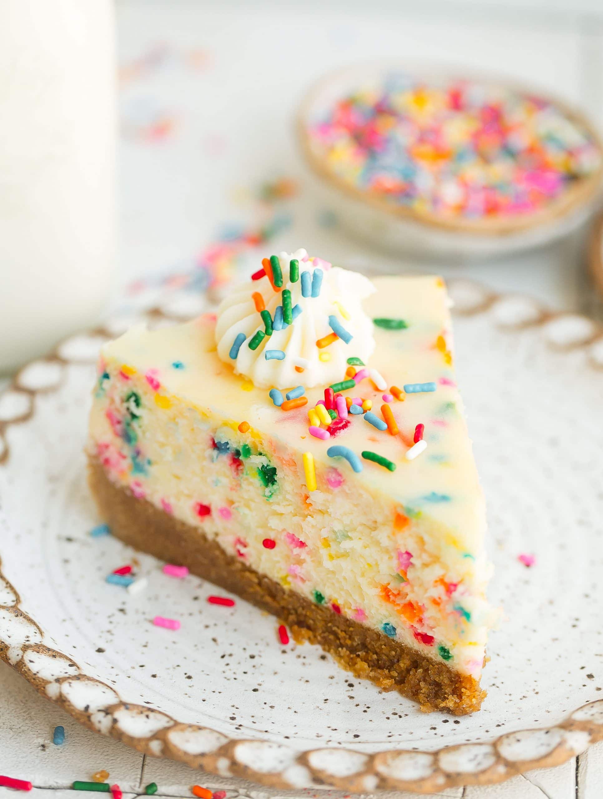 Slice of cheesecake on plate with sprinkles.