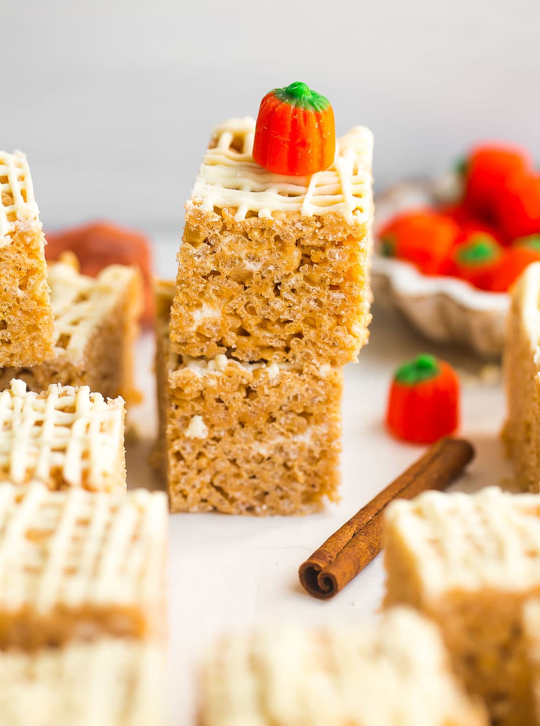 Stack of pumpkin spice rice krispie treats with drizzled white chocolate and pumpkin candy.