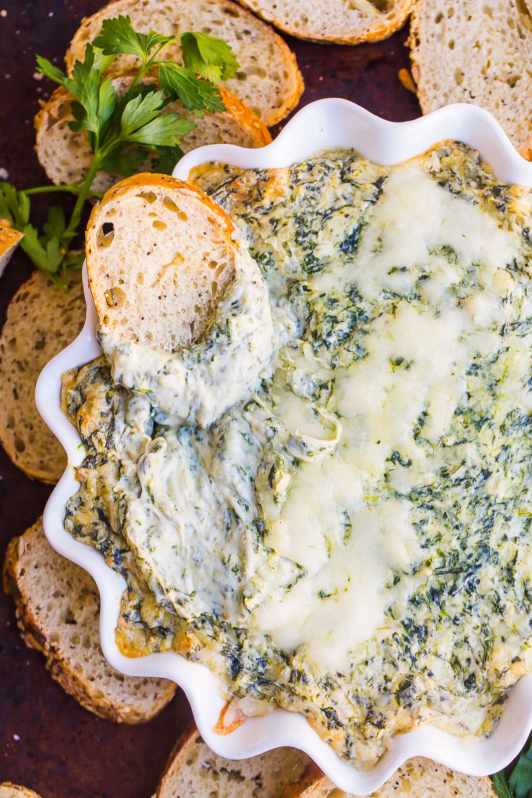 Bread dipped in a bowl of cheesy spinach dip. 