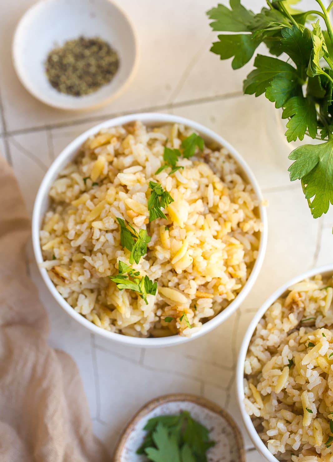 Two bowls of rice with parsley on top.