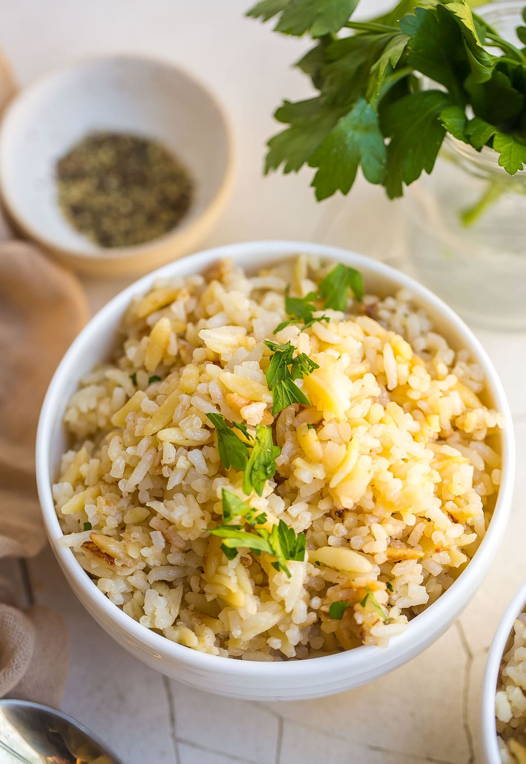 Rice pilaf in a white bowl with chopped parsley on top. 
