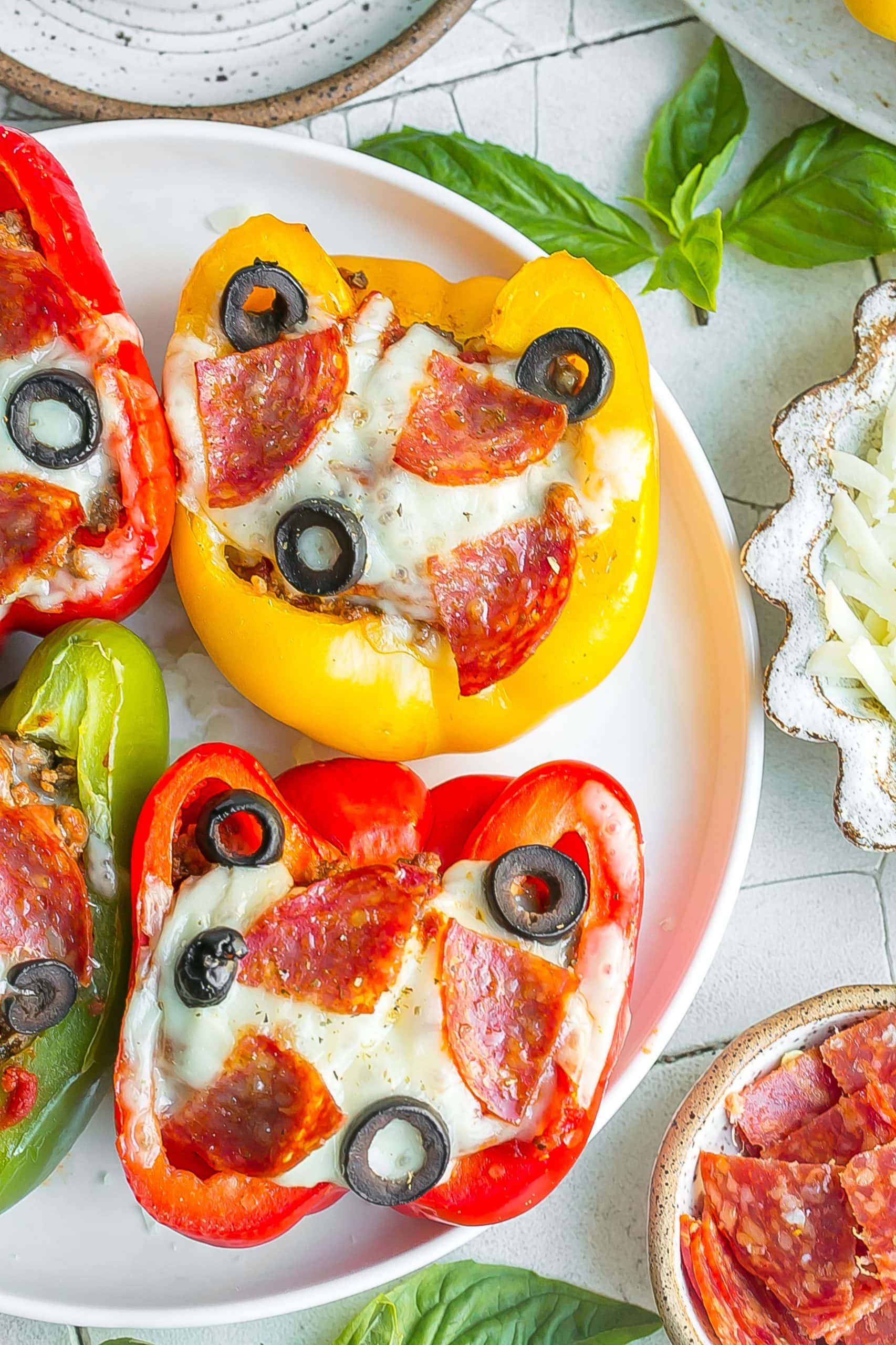 Pepperoni, olive and cheese stuffed bell peppers on a plate.