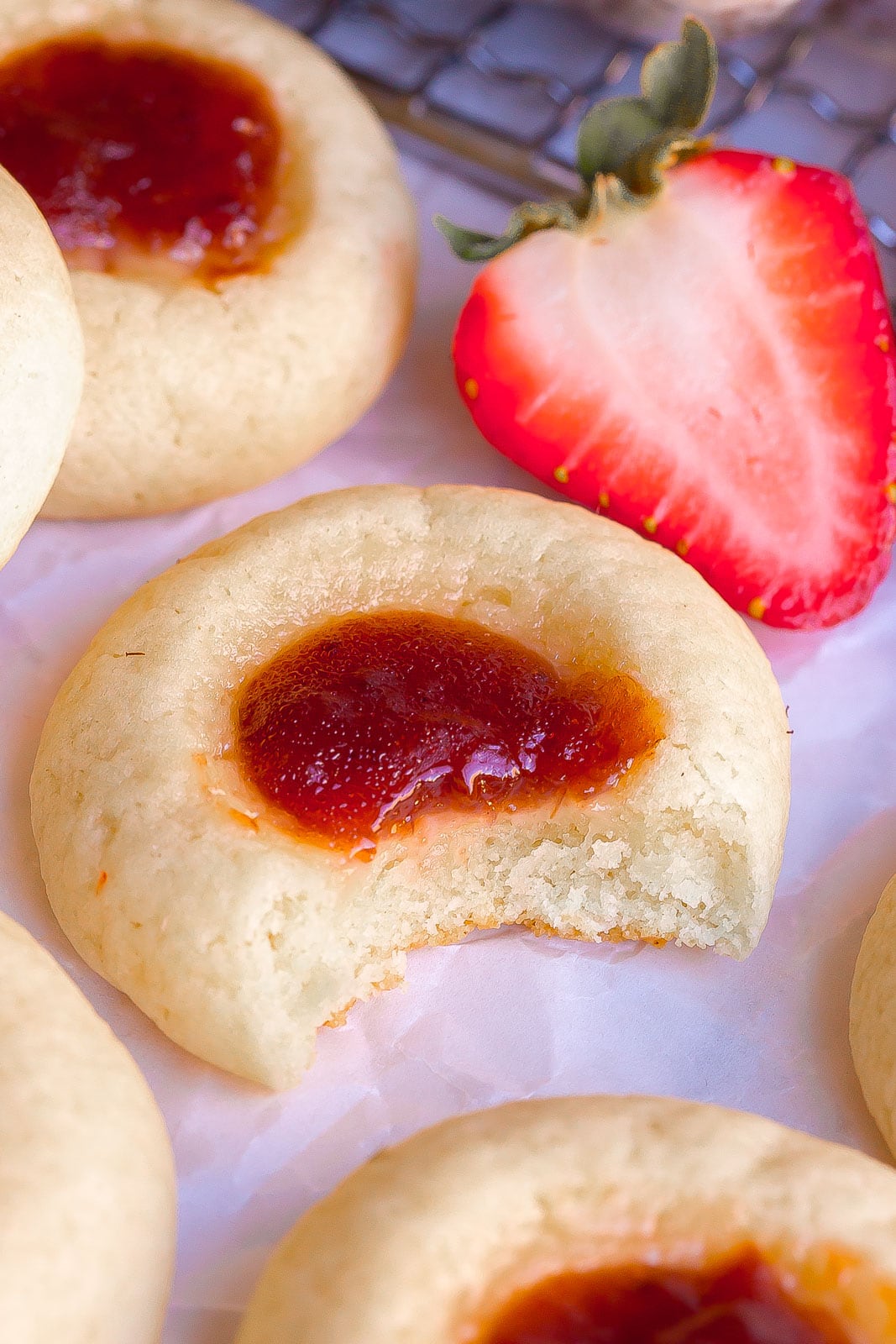 Close up of Thumbprint cookie with bite mark on parchment paper. 