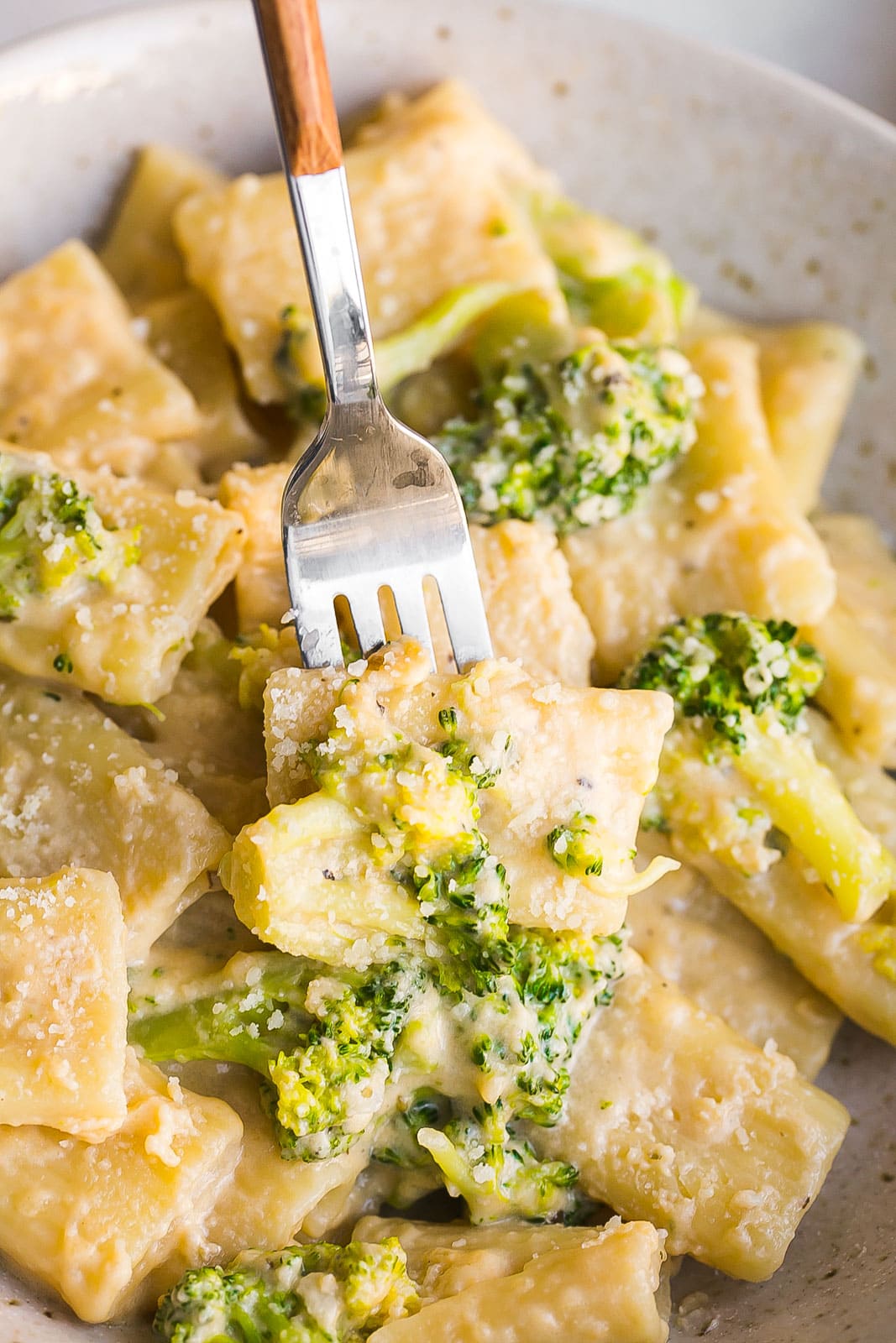 Cheesy pasta with broccoli on a fork.