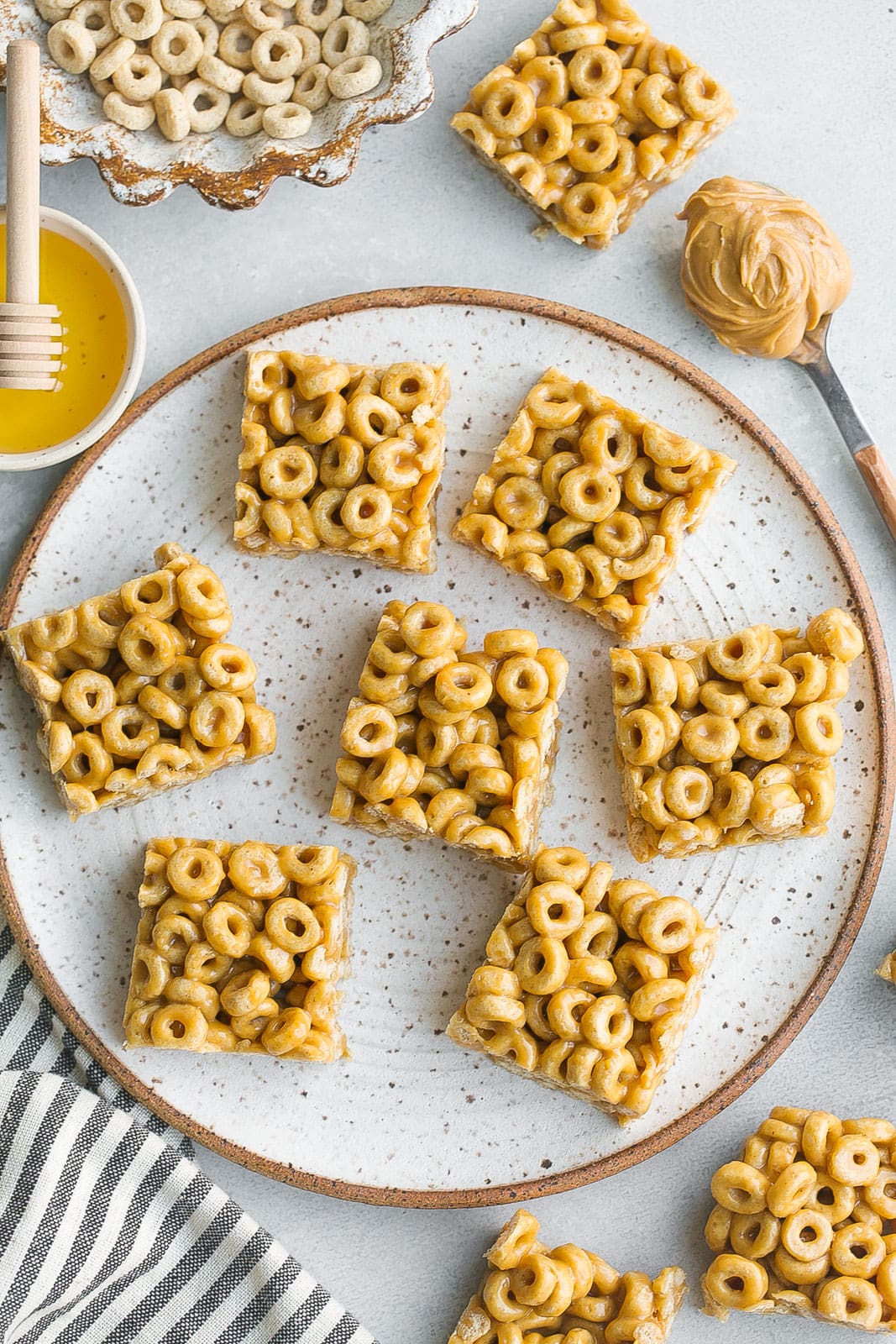 Cereal bars on plate with cheerios, honey and peanut butter.