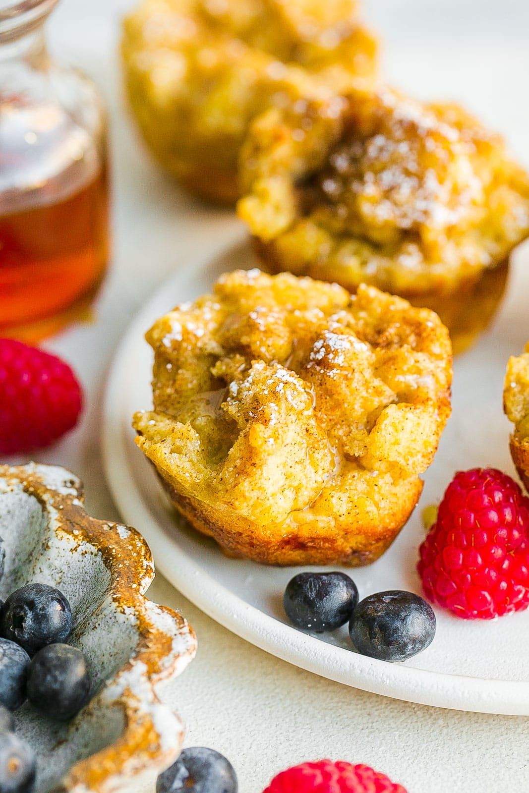 French toast muffins with fresh berries on a white plate.