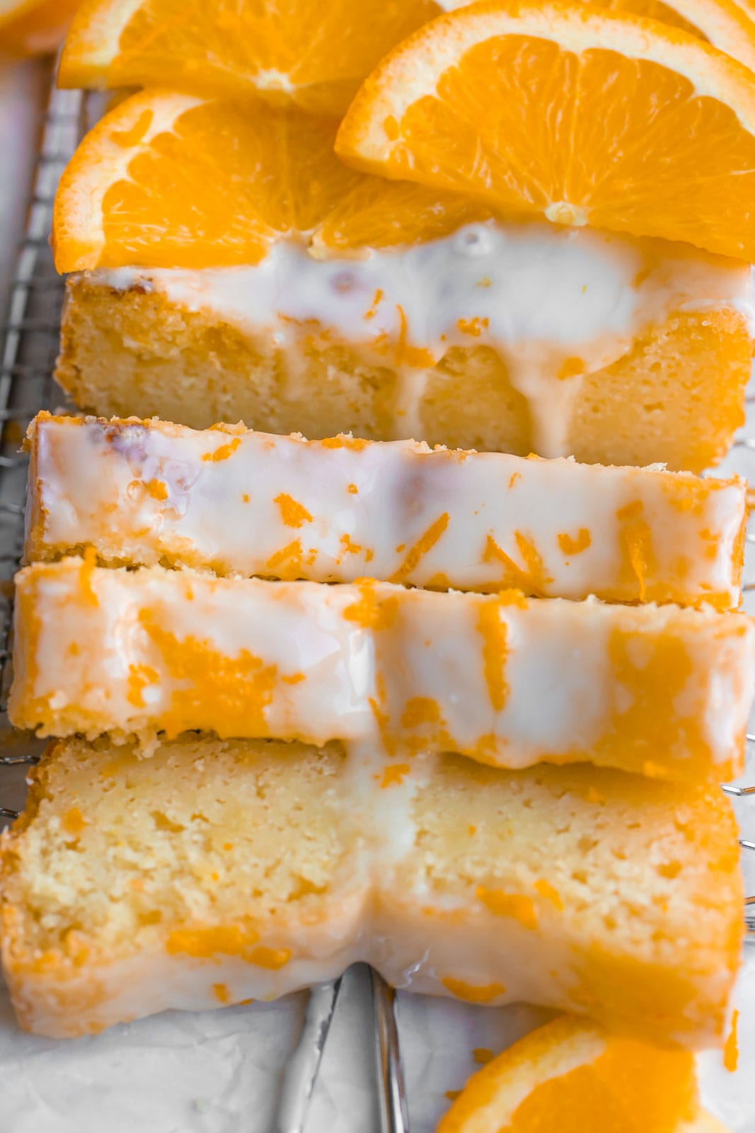 Sliced of orange loaf cake with orange zest on top.