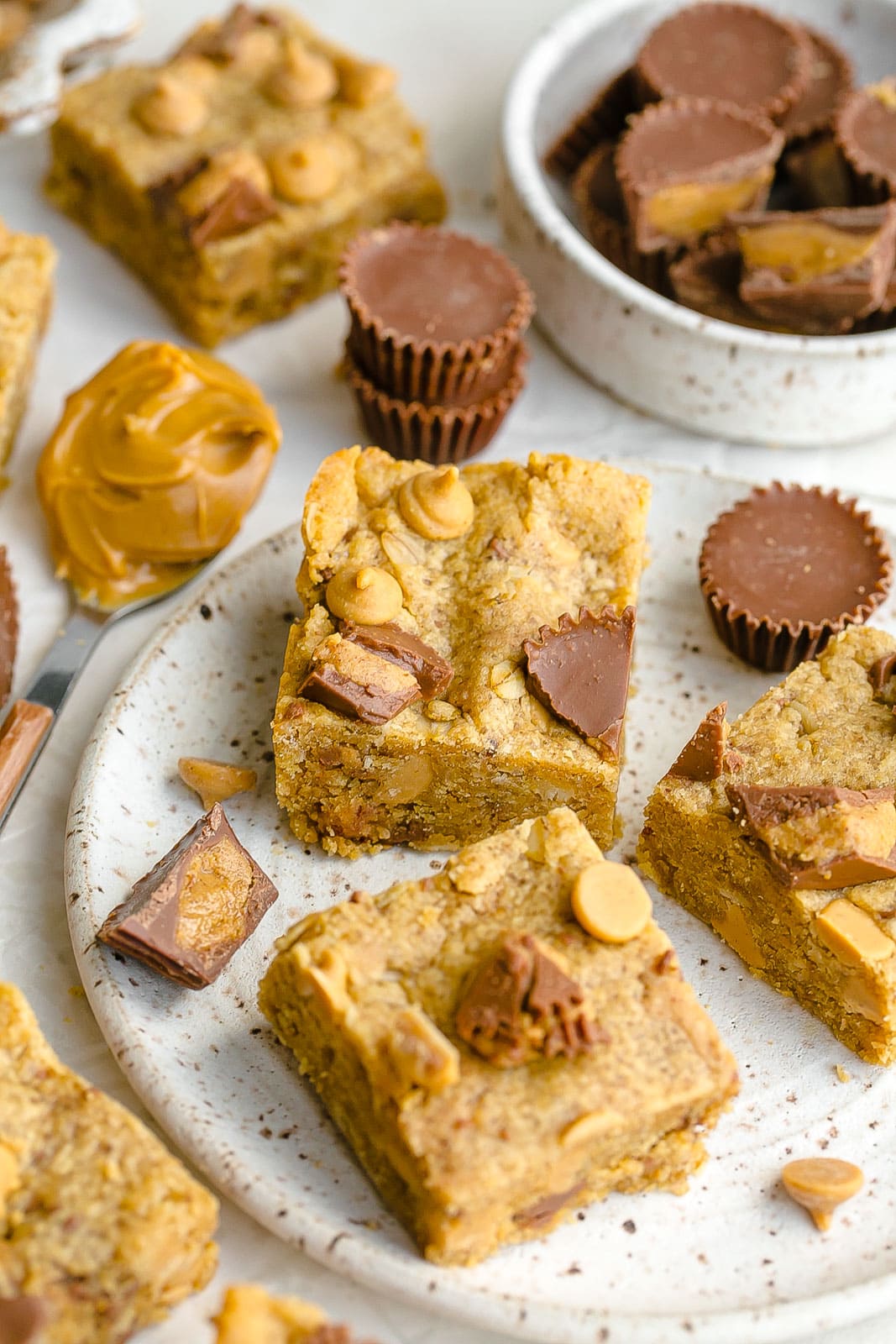 Peanut butter cup bars on a plate with a spoonful of peanut butter.