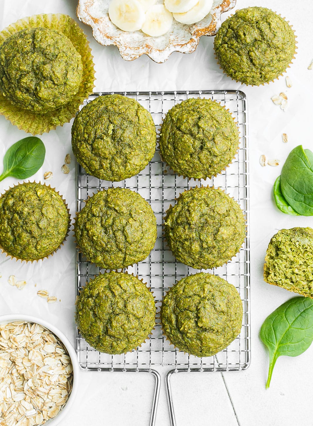 Muffins on a cooling rack with spinach and oats.