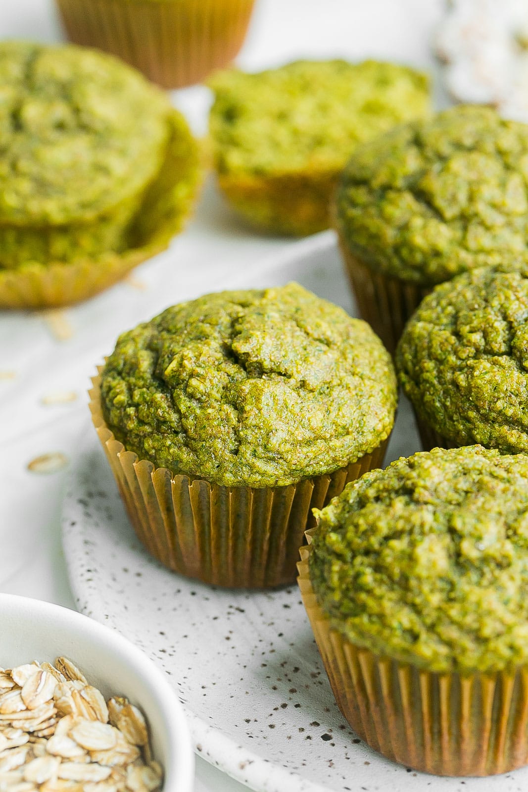 Green banana muffins on plate with oats. 