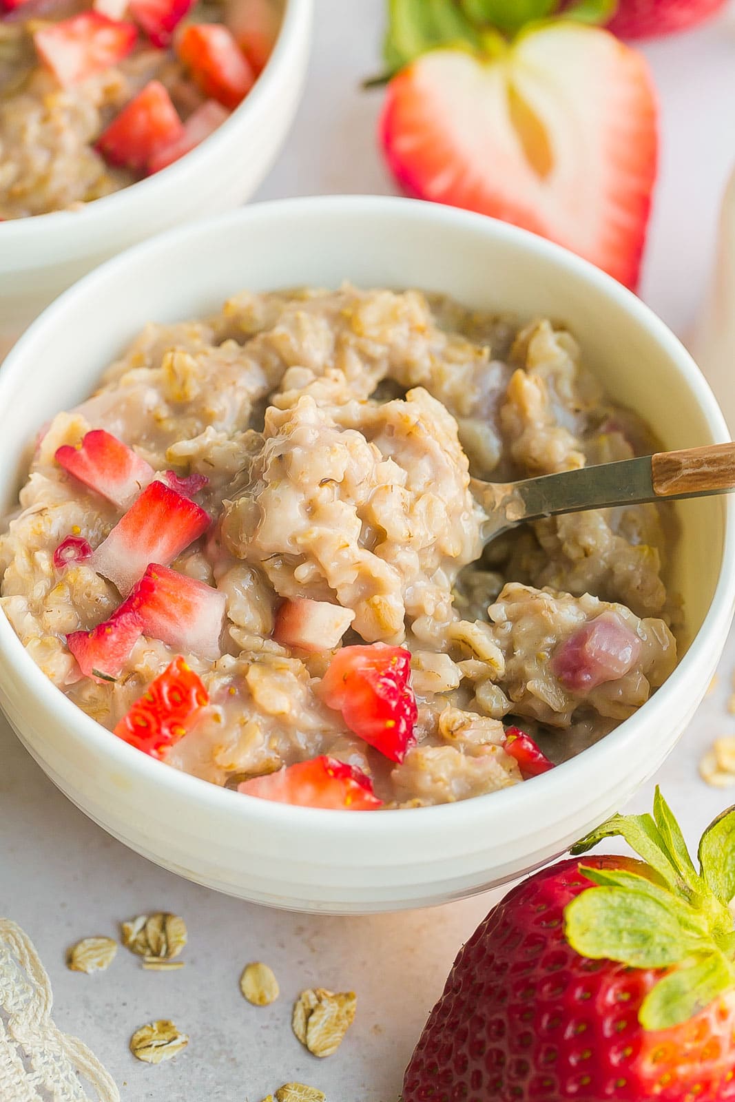 Oatmeal with strawberries on a spoon.