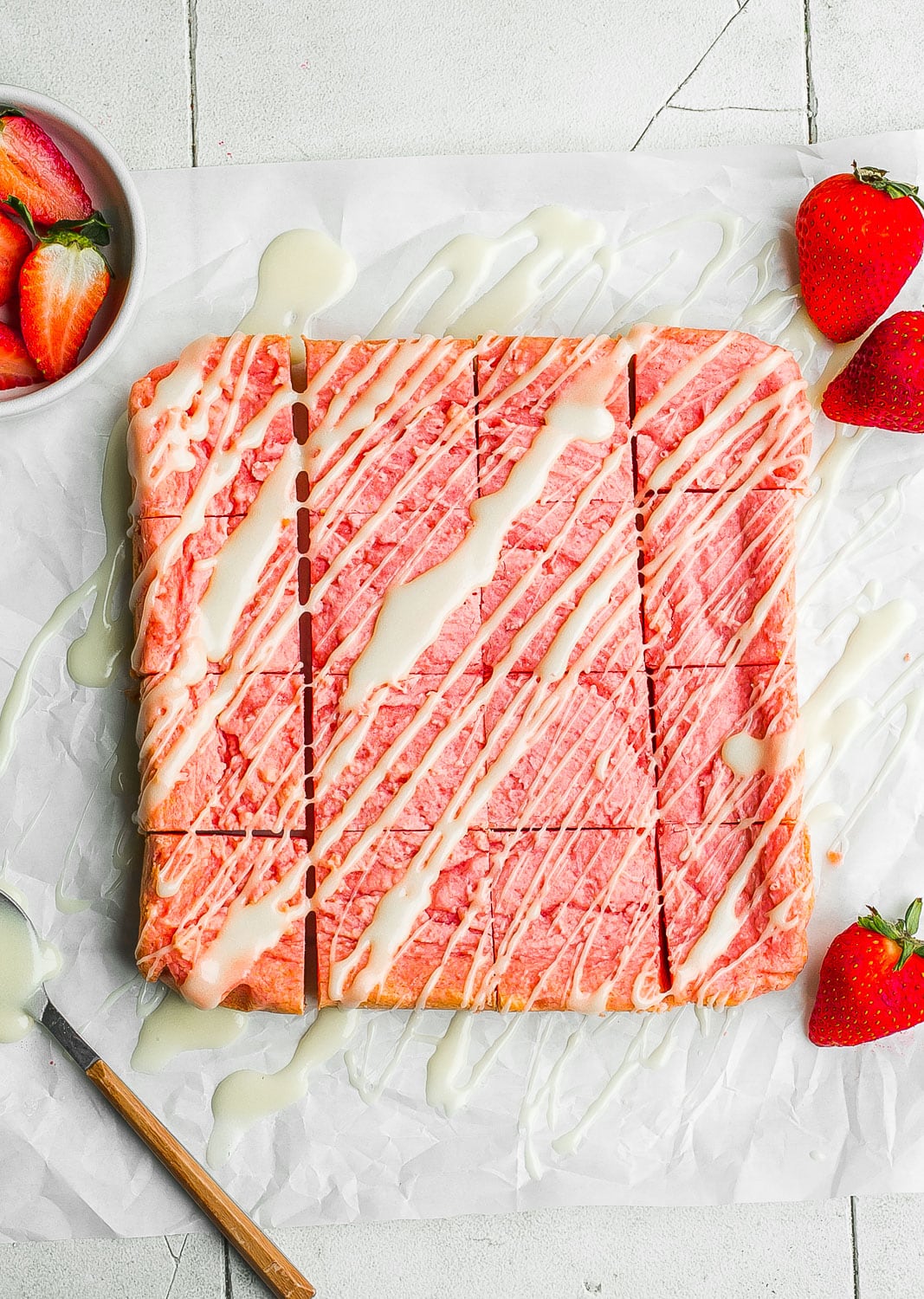 Strawberry brownies cut into squares with icing on top.