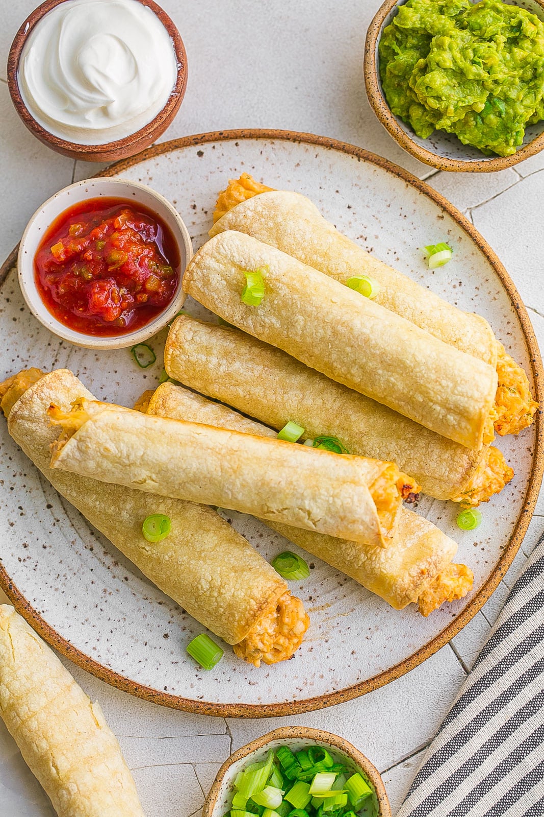 Taquitos on a plate with a side of salsa.