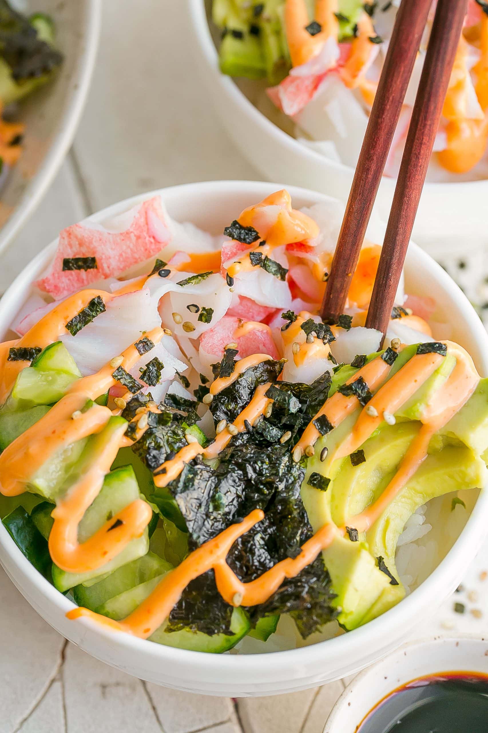 Close up of sushi bowl with chopsticks.